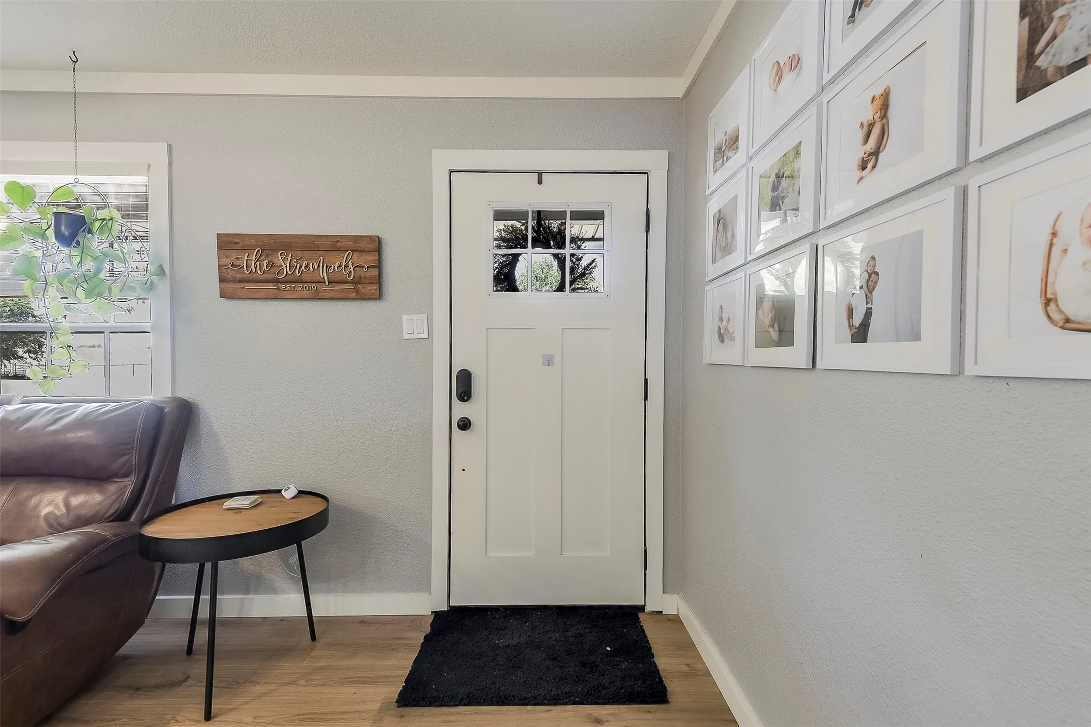 White entry door with multi-pane window, Wood-finish flooring, and light gray wall paint
