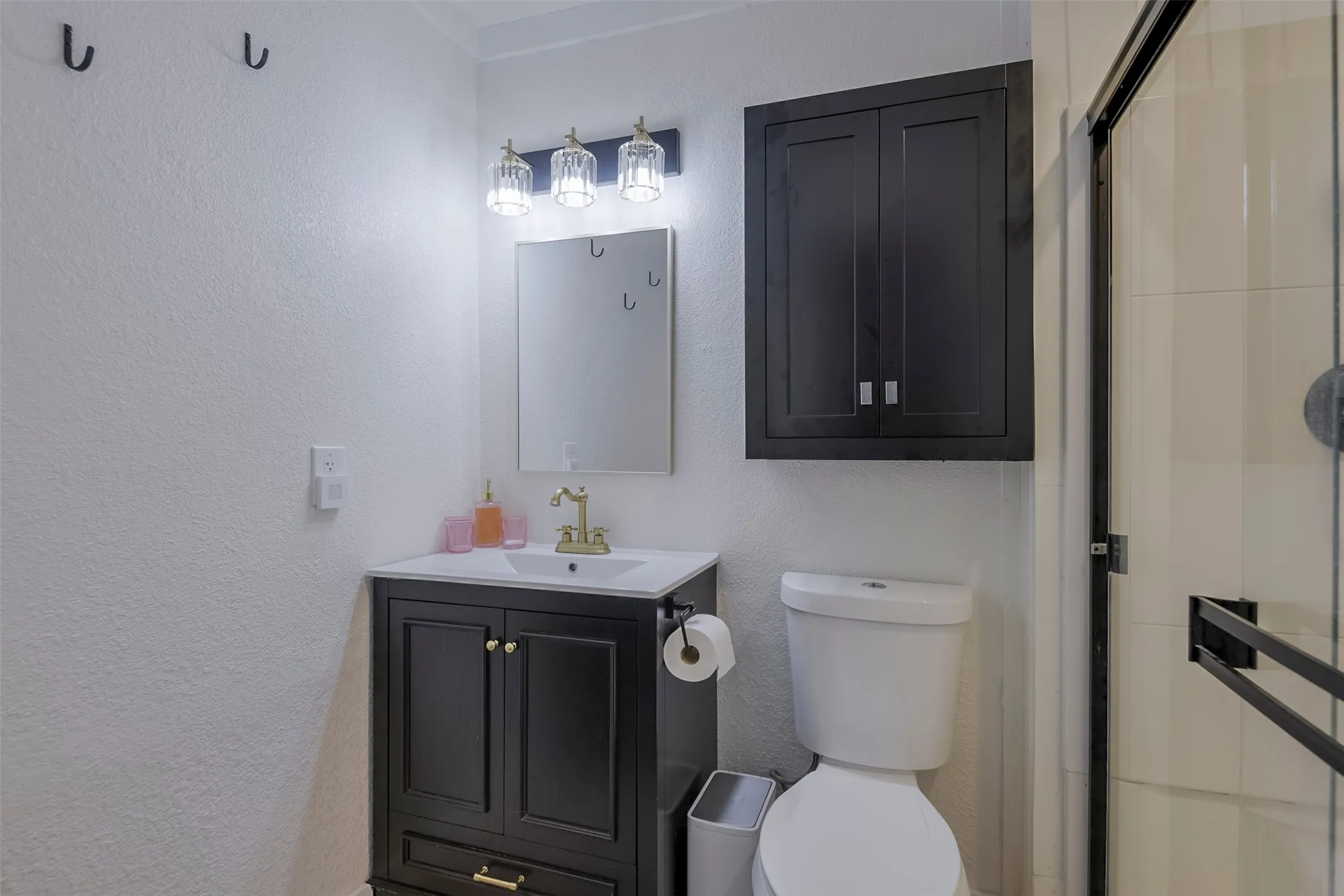 Bathroom featuring a dark wood-finish vanity with a white countertop, a wall-mounted mirror, and a three-light fixture