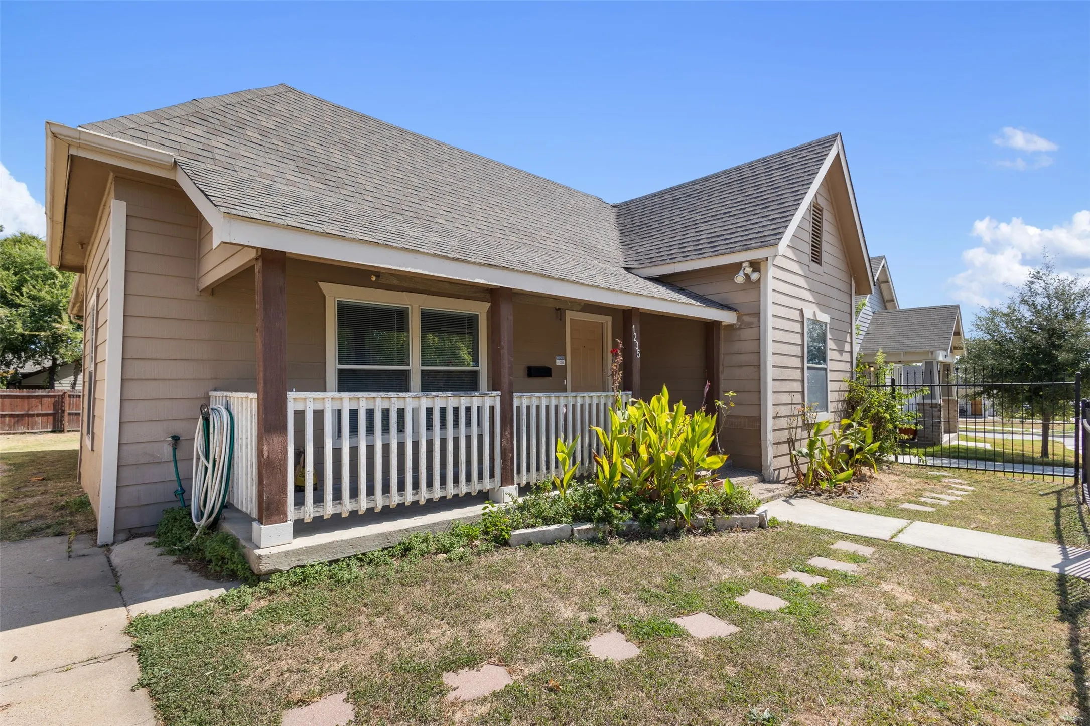 Siding exterior with a covered porch, white railing, and a gabled roof