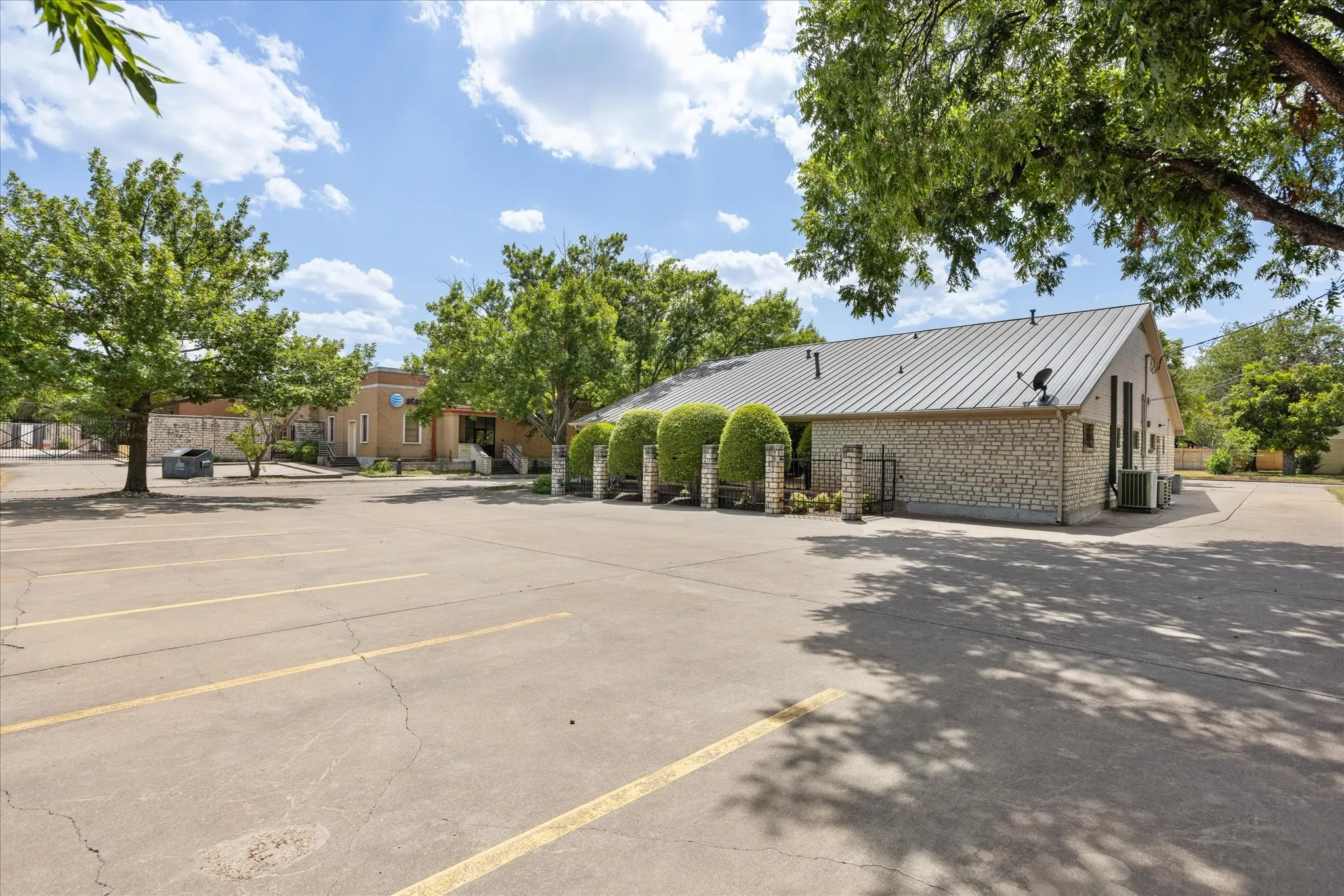 Expansive paved parking area, stone-clad exterior with a metal roof, and manicured shrubbery