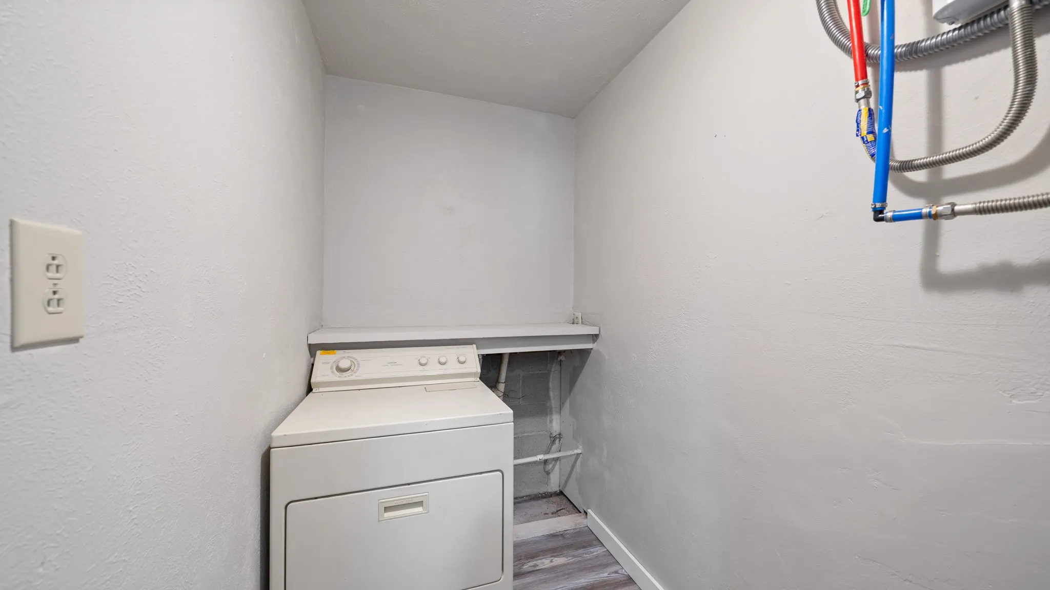 Laundry area with wood-finish flooring and a built-in shelf