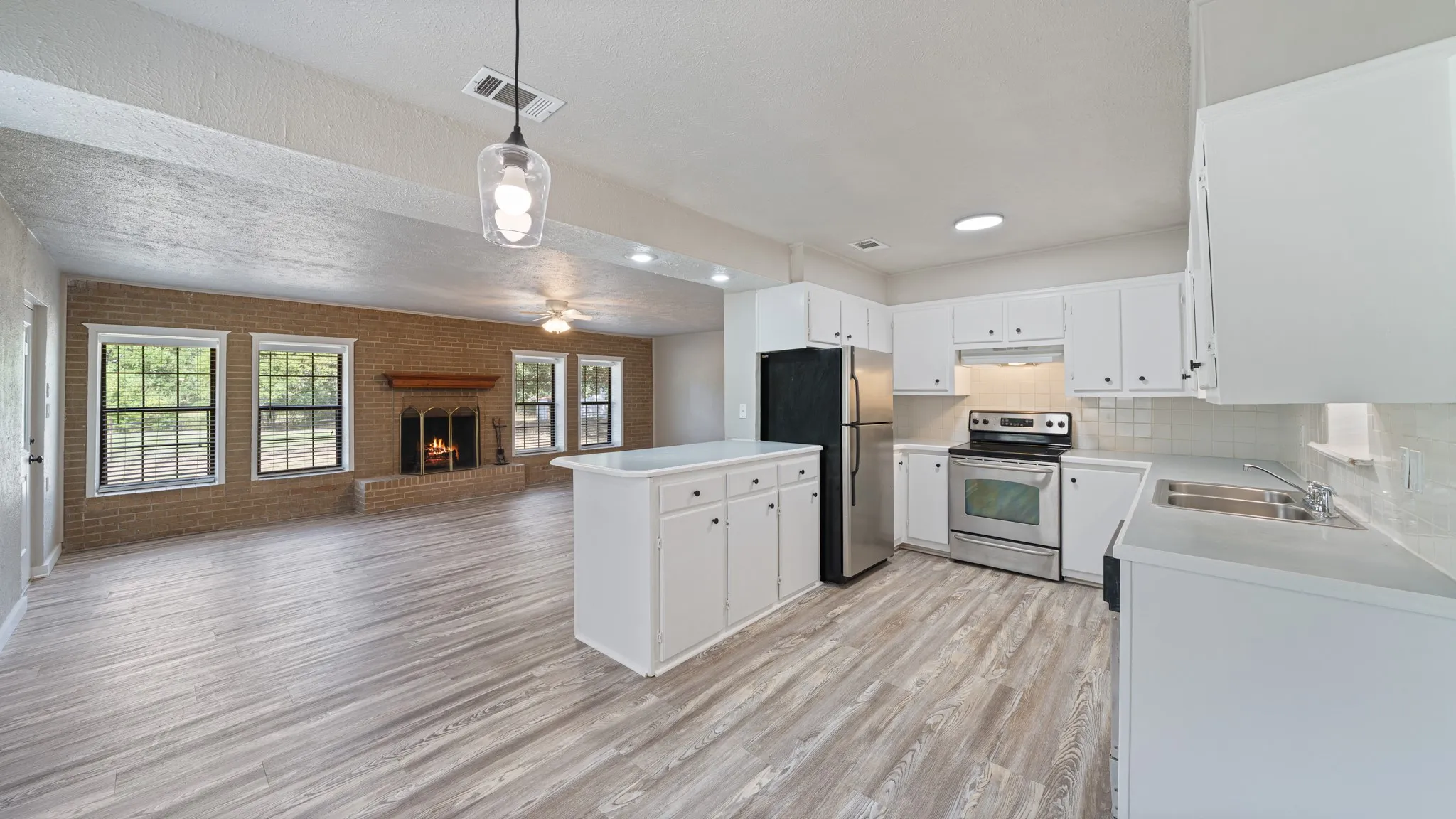 Open-concept kitchen featuring white cabinetry, stainless steel appliances, and a central island