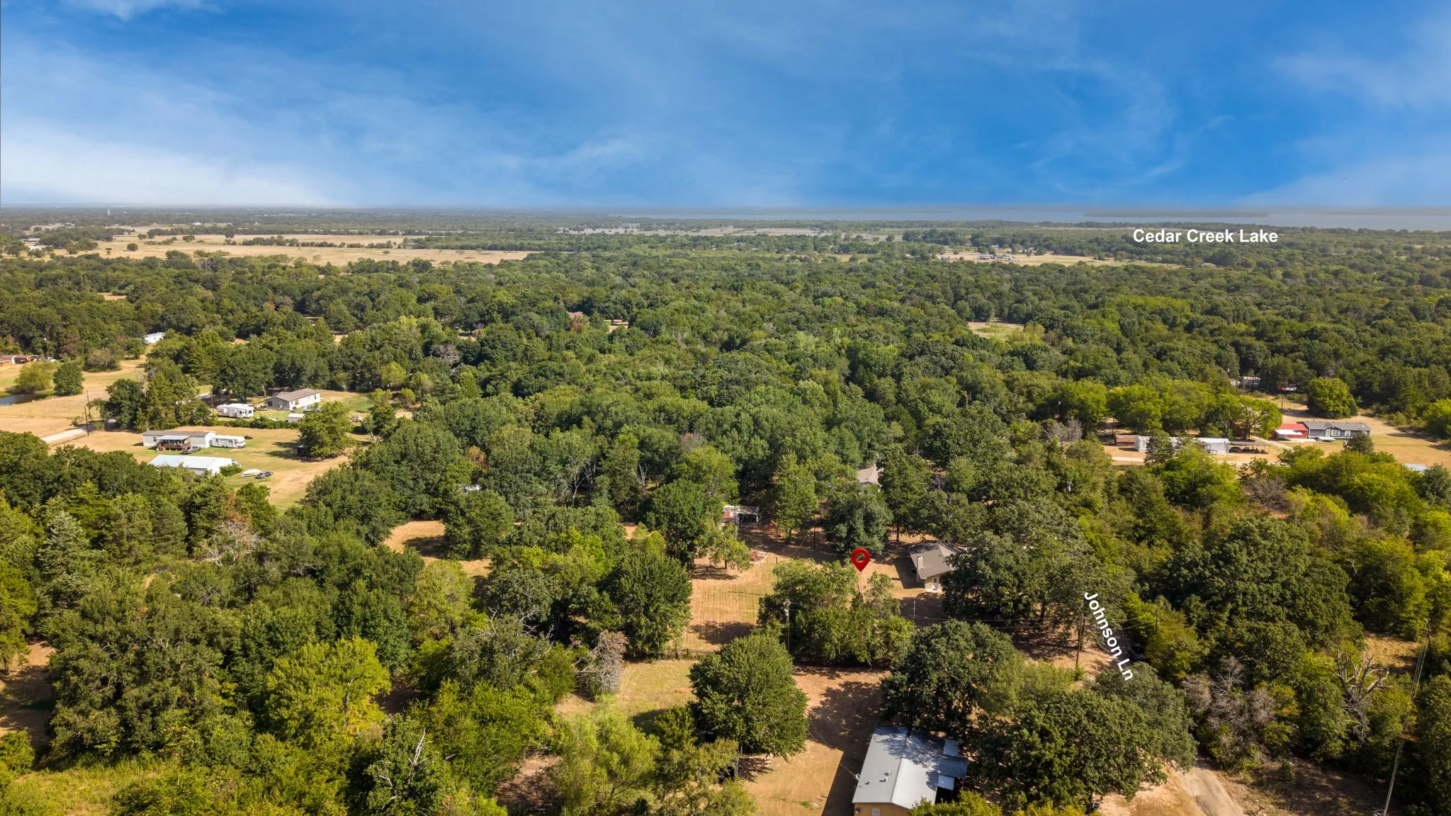 Expansive land parcel with dense tree coverage, featuring a visible structure