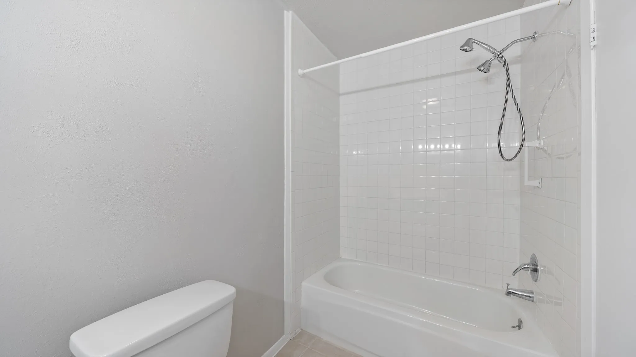 Bathtub with white tile surround and chrome fixtures