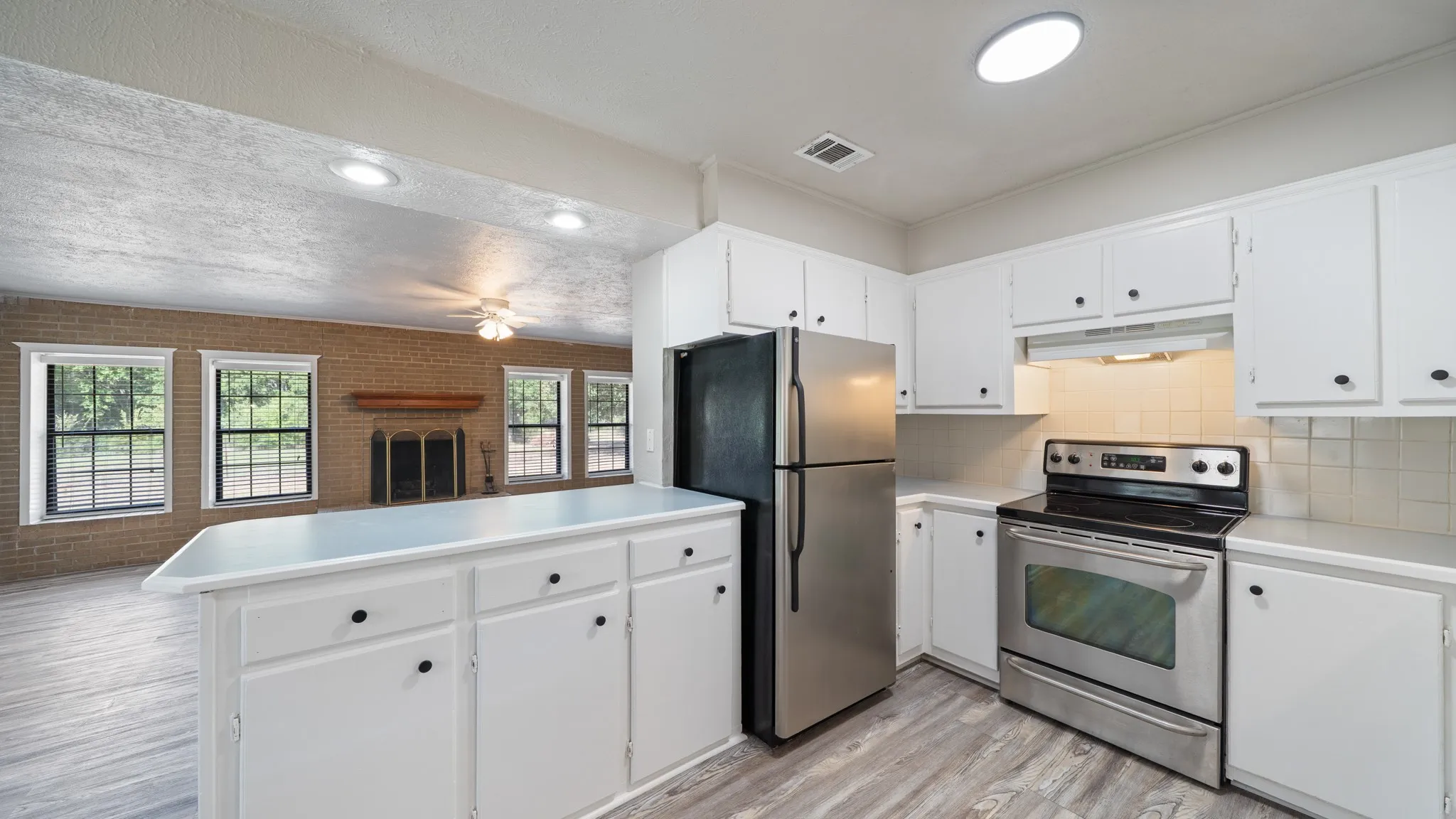 Kitchen featuring white cabinetry, light-toned countertops, and stainless steel appliances