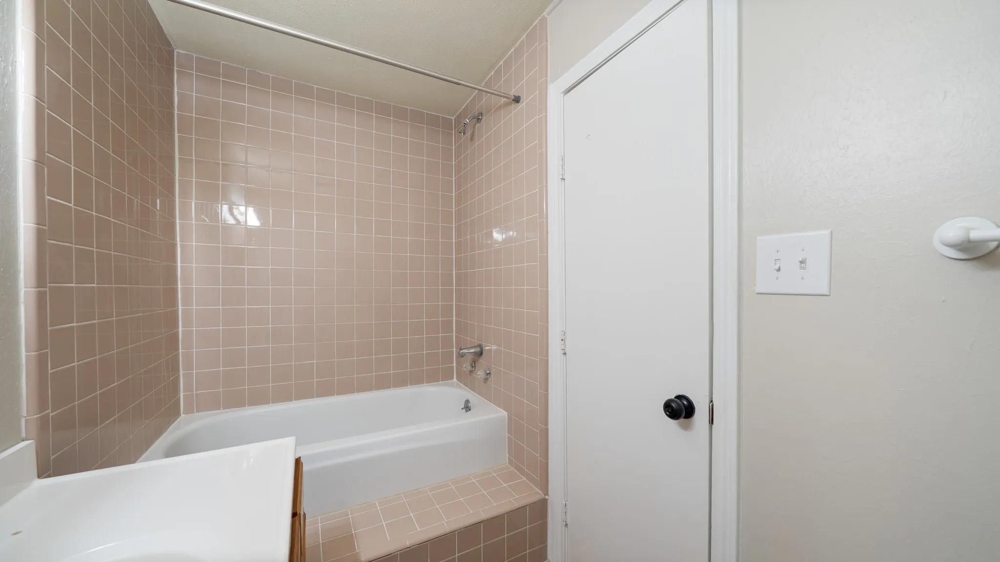 White bathtub with chrome fixtures and light-toned tile surround