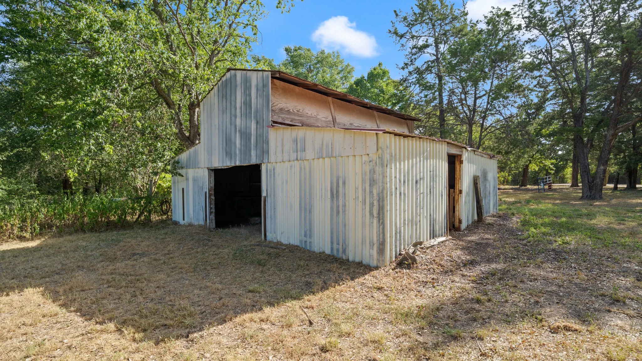 Corrugated metal barn structure with a gambrel roof and open access points