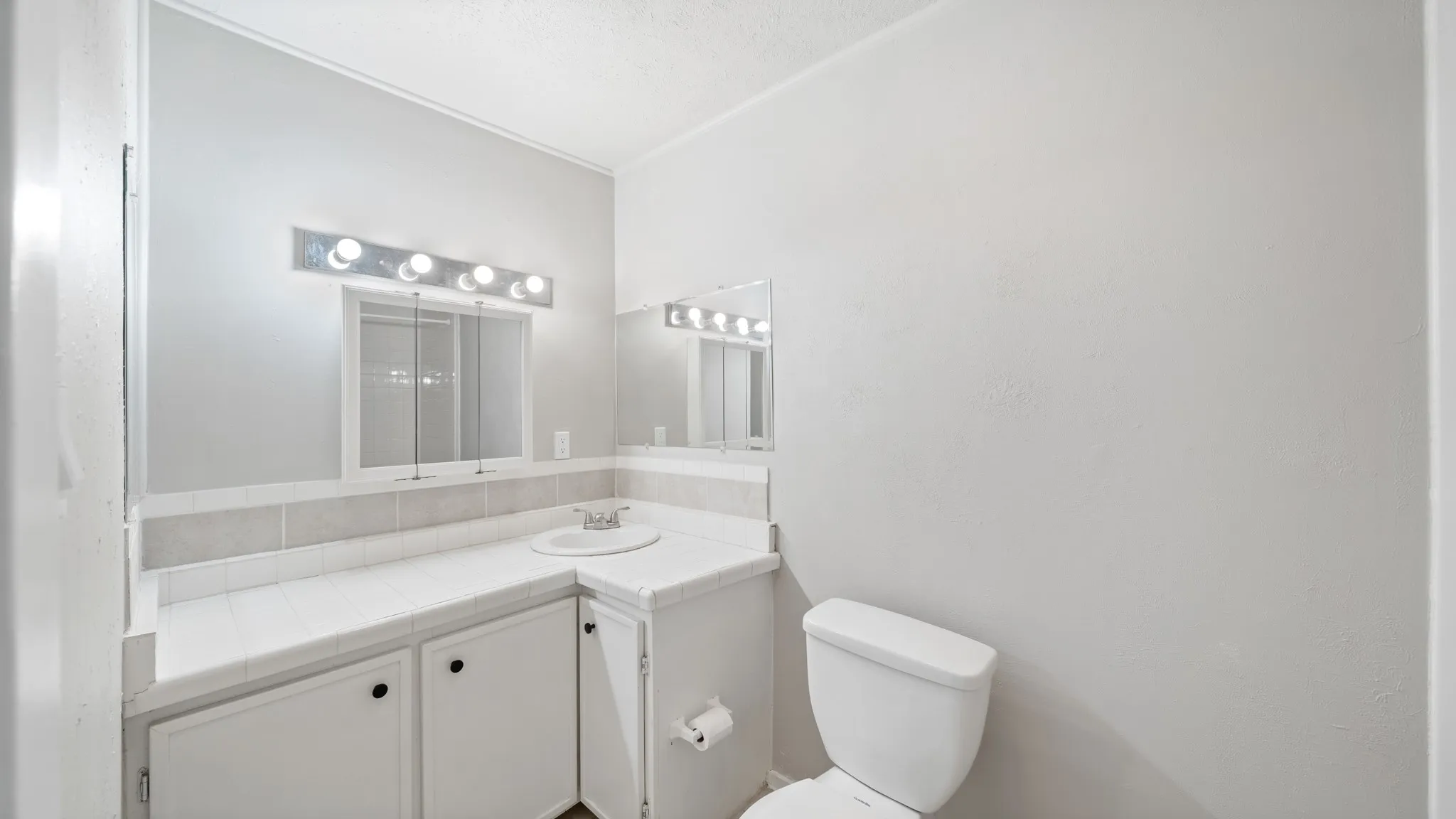 Bathroom featuring a vanity with an integrated sink, built-in cabinetry, tiled countertops, and a medicine cabinet with vanity lighting