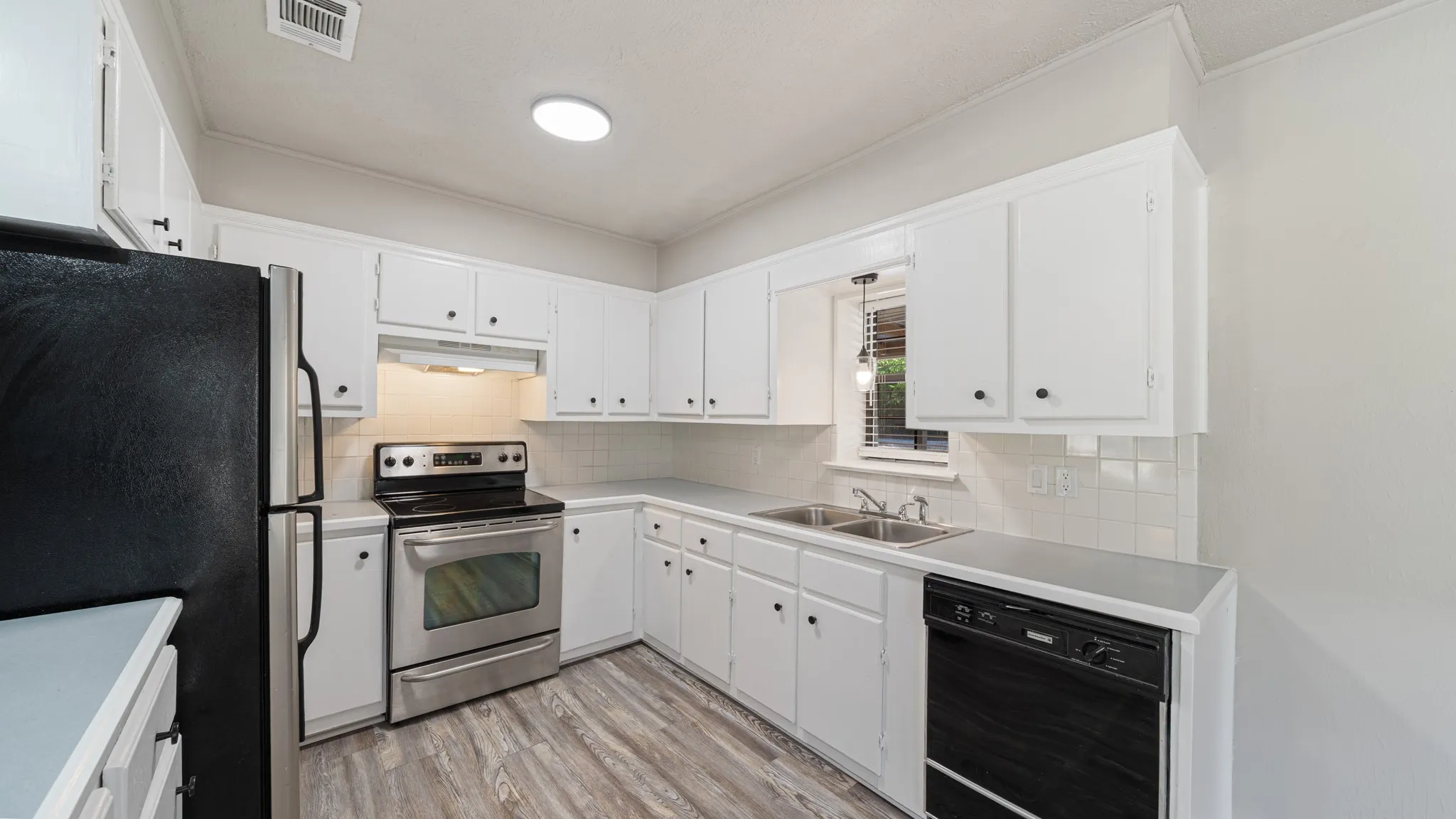Updated kitchen with white cabinetry, stainless steel range, dual basin sink, and wood-finish flooring