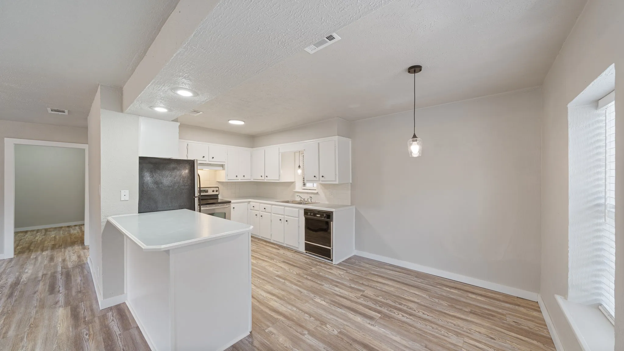 Kitchen featuring white cabinetry, light countertops, stainless steel appliances, and wood-finish flooring