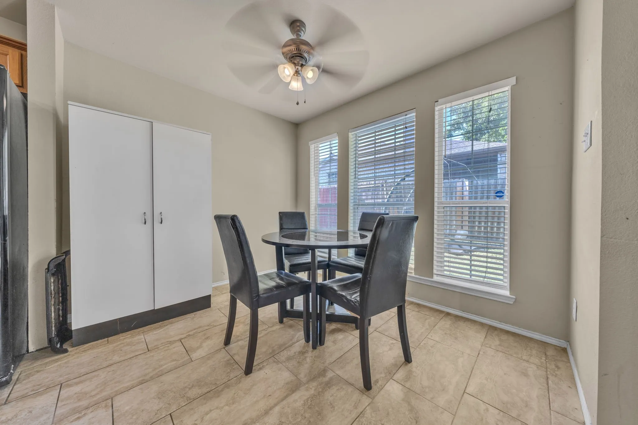 Ceramic tile flooring, white vertical storage cabinetry, multiple windows, and a ceiling fan with integrated lighting