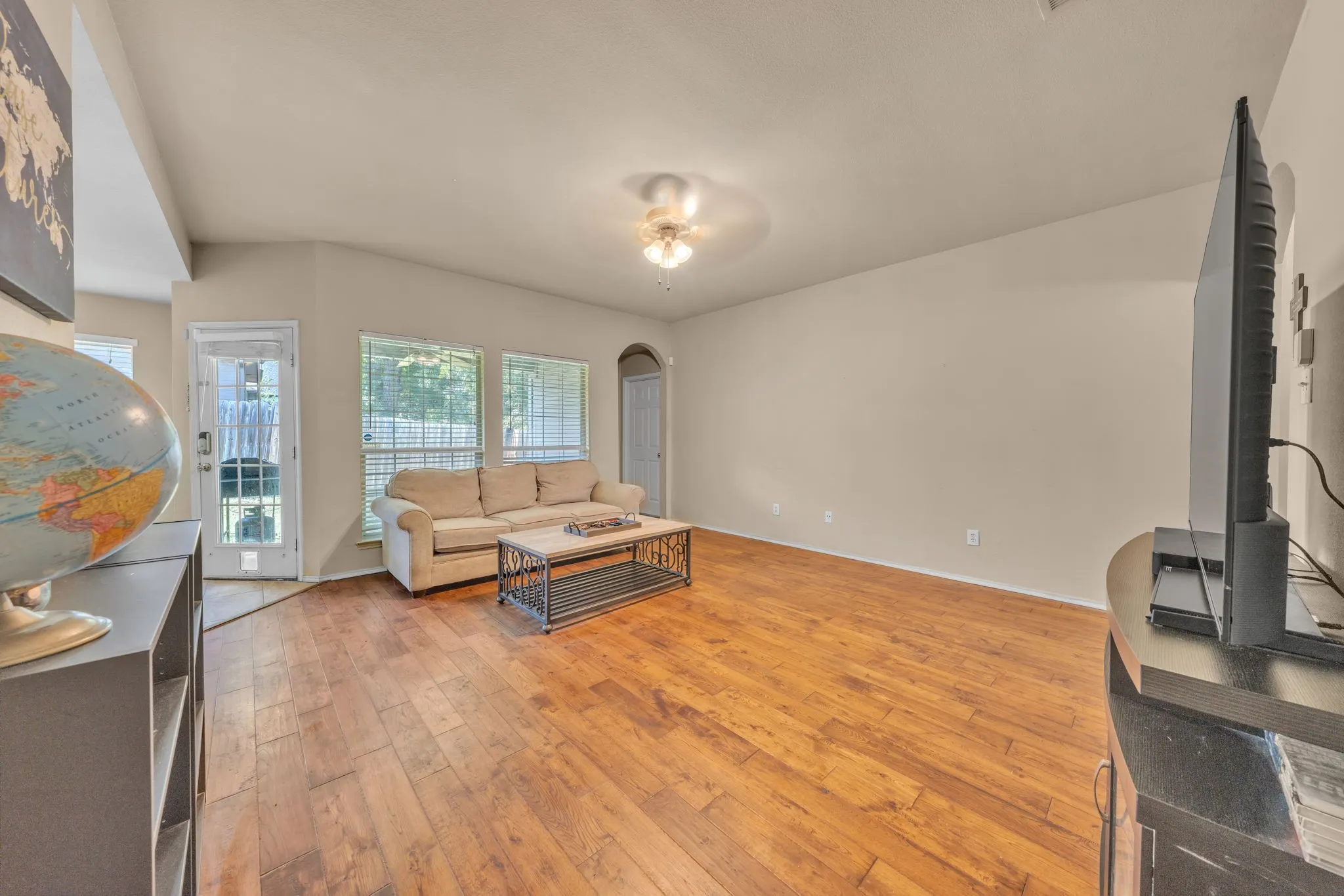 Vaulted ceiling featuring a ceiling fan, wood-finish flooring, and multiple windows with blinds