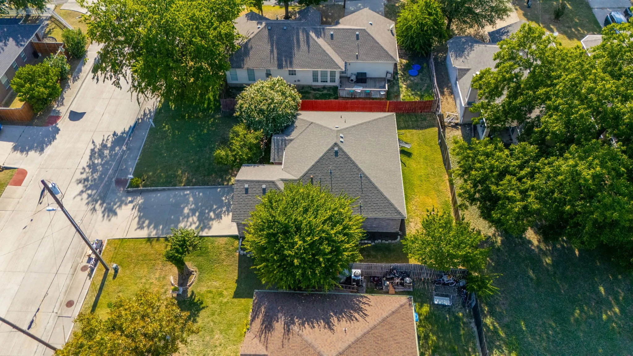 Manicured lawn with established trees, paved street, and surrounding properties