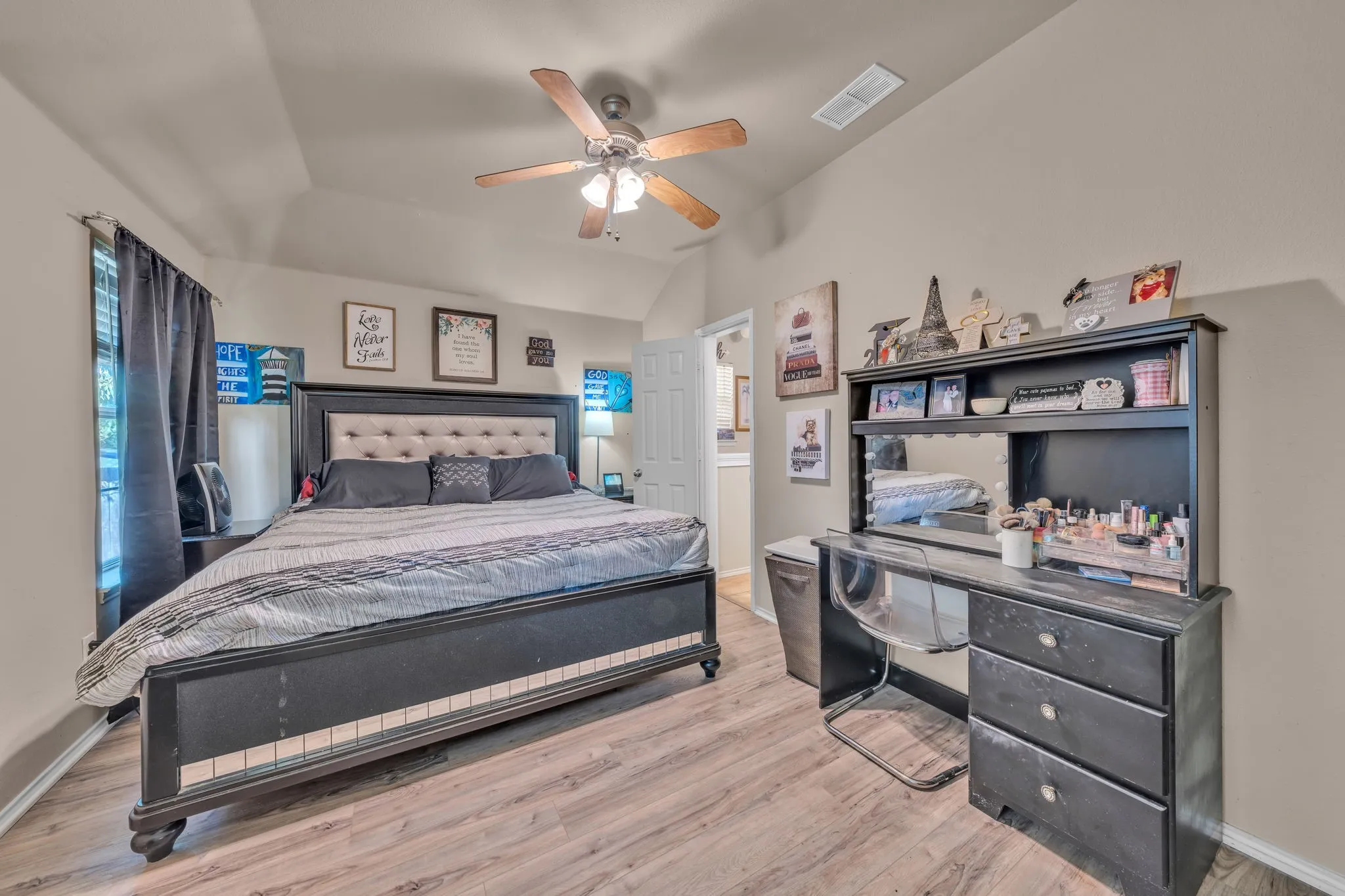 Vaulted ceiling featuring a ceiling fan with integrated lighting, wood-finish flooring, and window with blinds