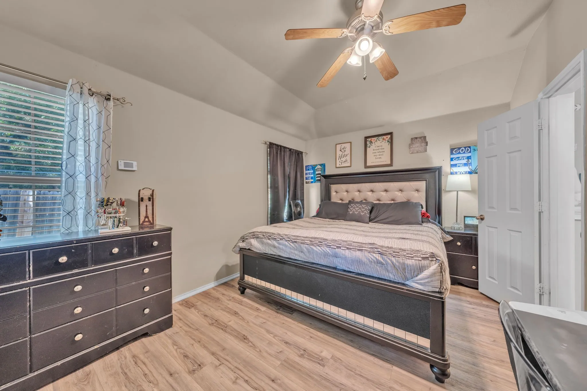Vaulted ceiling with a ceiling fan, wood-finish flooring, and natural light from a window with blinds