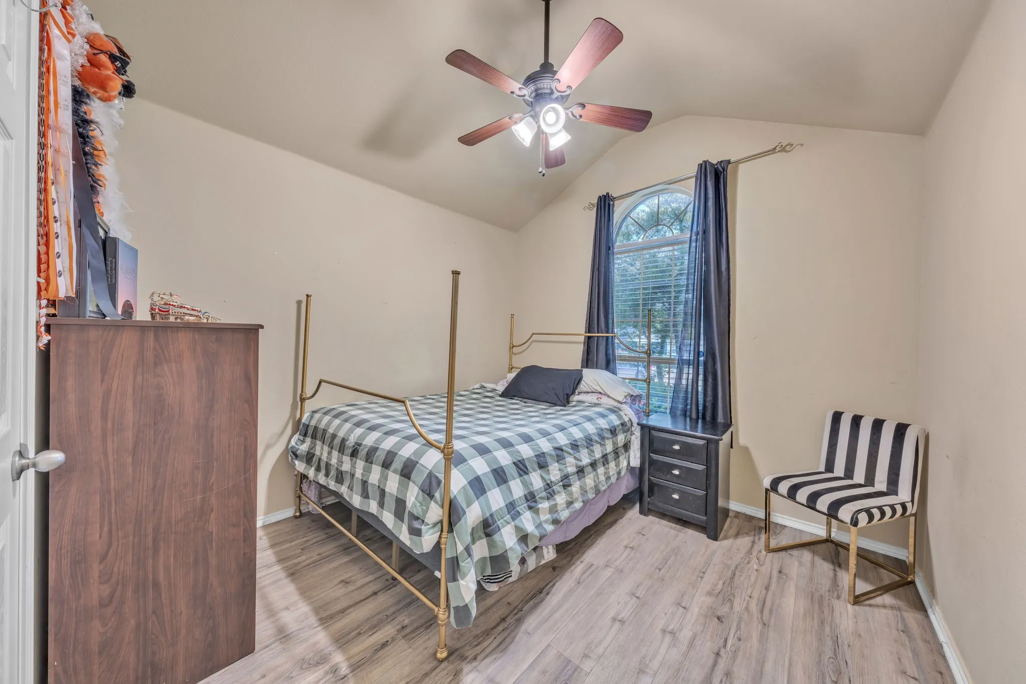 Room featuring a vaulted ceiling with a ceiling fan, wood-finish flooring, and an arched window
