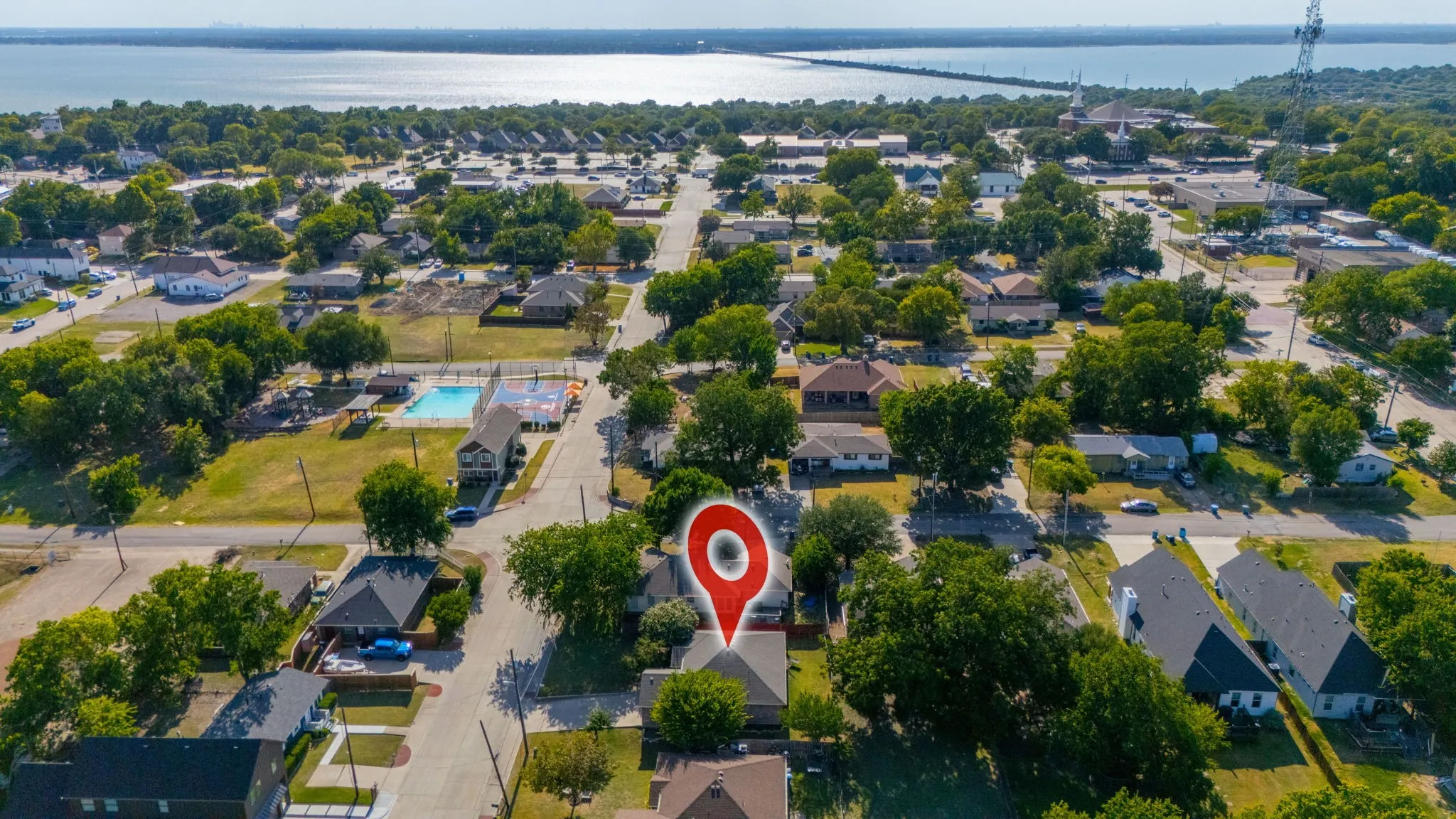 Aerial perspective of a residential neighborhood featuring established homes, mature trees, and proximity to a large body of water