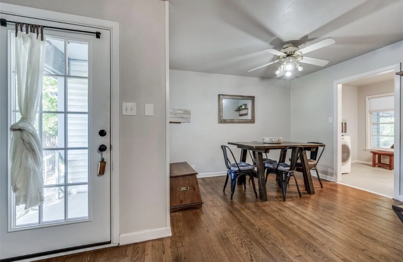Wood-finish flooring, white walls, ceiling fan with integrated lighting, glass-paneled exterior door, and an open doorway