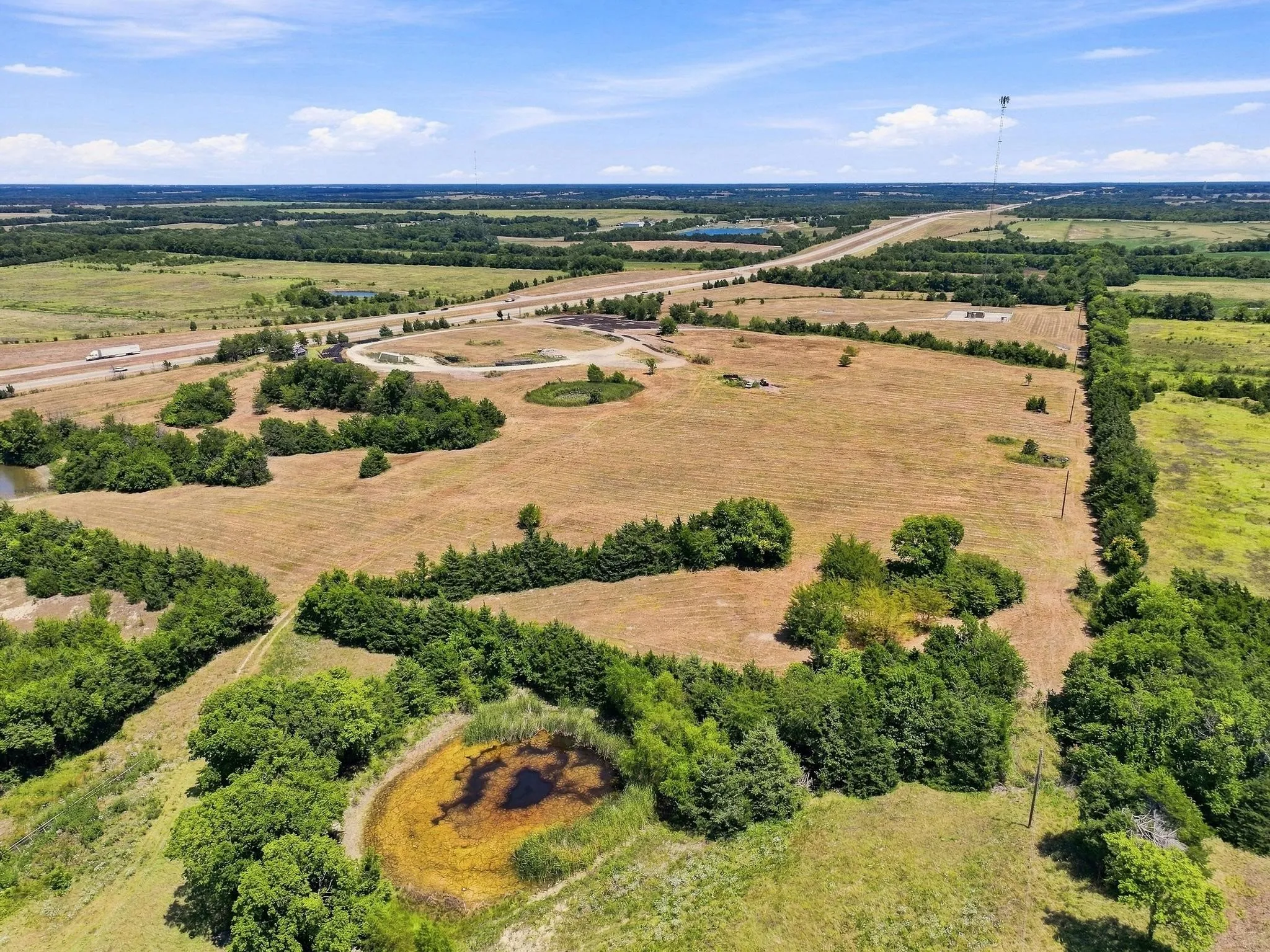 Expansive land featuring multiple ponds, mature trees, and a visible highway frontage