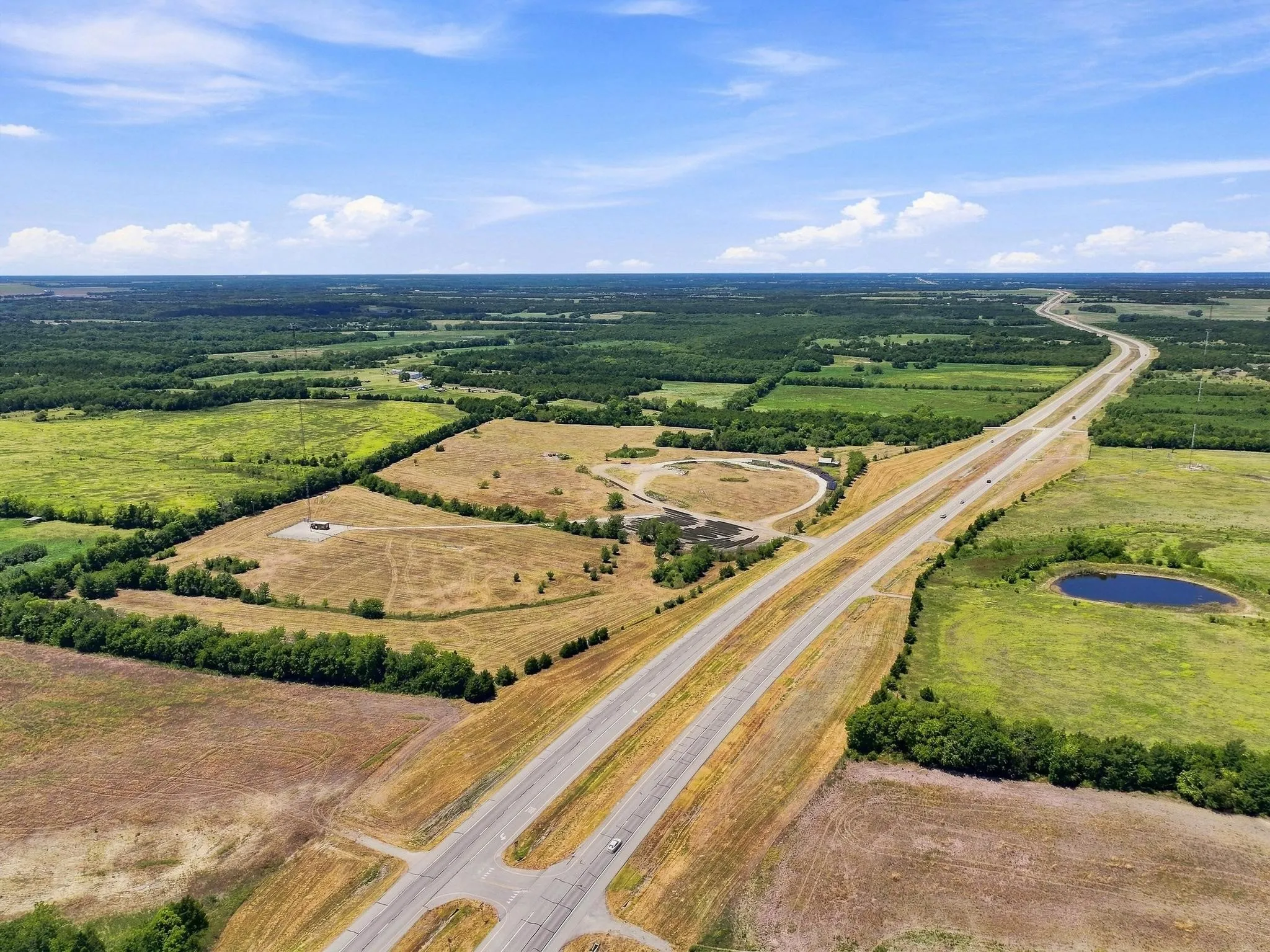 Expansive land parcel featuring open fields, mature tree lines, and a visible roadway