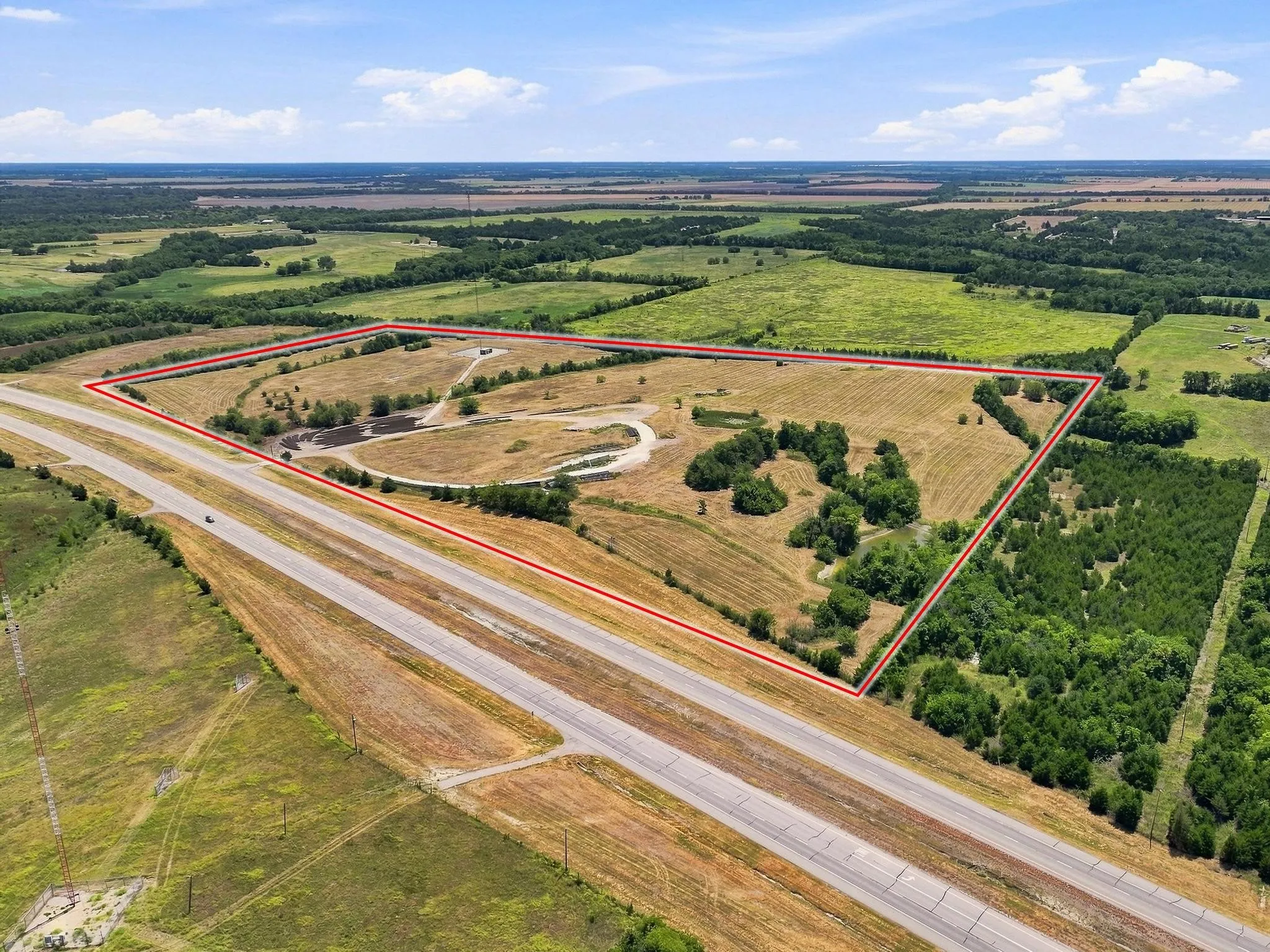 Expansive land parcel featuring open fields, multiple ponds, and mature tree clusters
