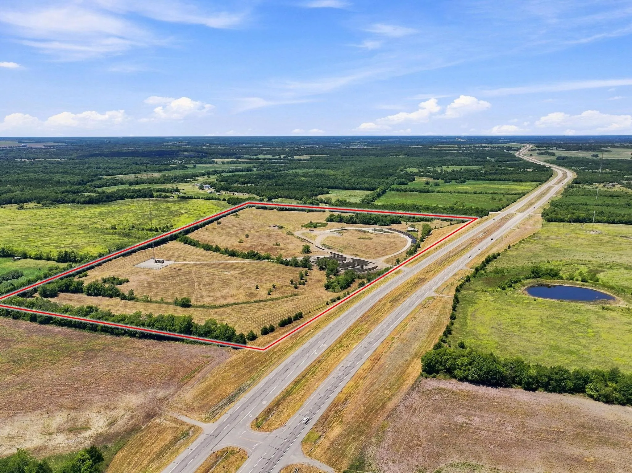 Expansive parcel featuring a large pond, adjacent highway access, and surrounding natural landscape