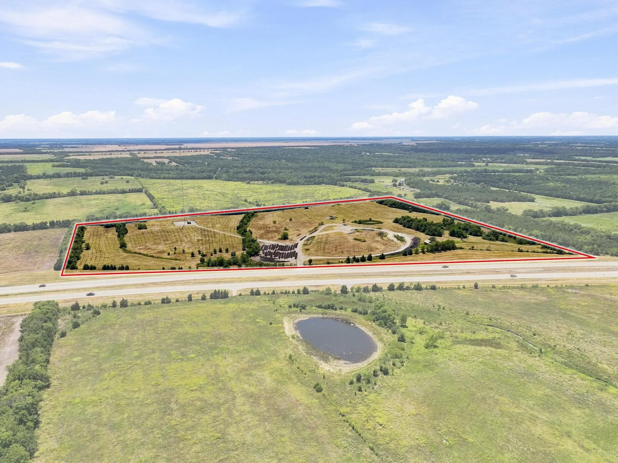Expansive land parcel with highway frontage, featuring diverse topography, established structures, and surrounding natural landscapes