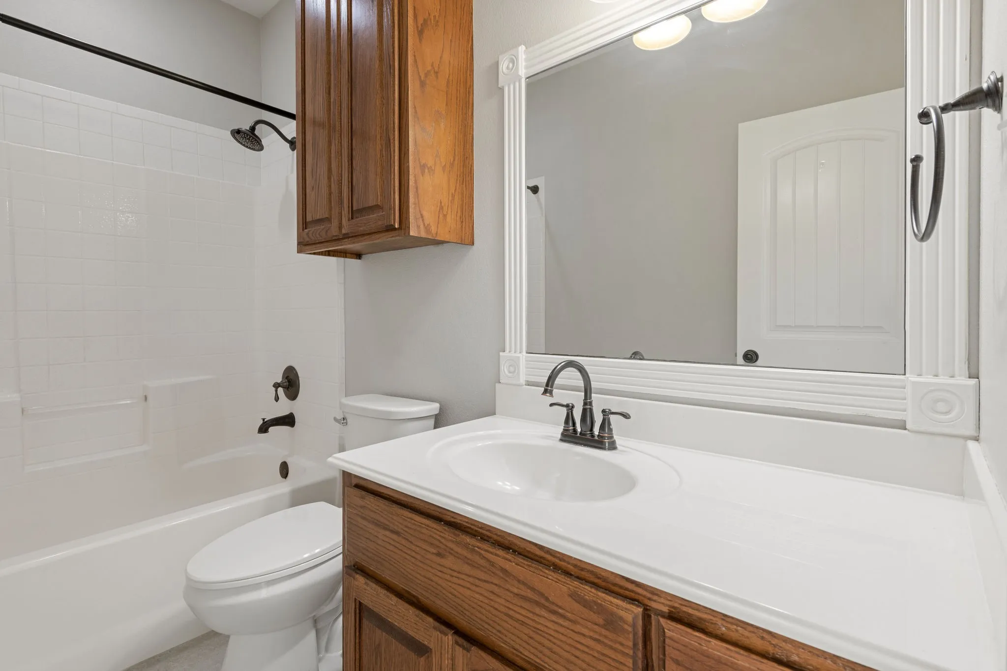 White vanity with integrated sink, bronze-finish fixtures, and coordinating hardware.