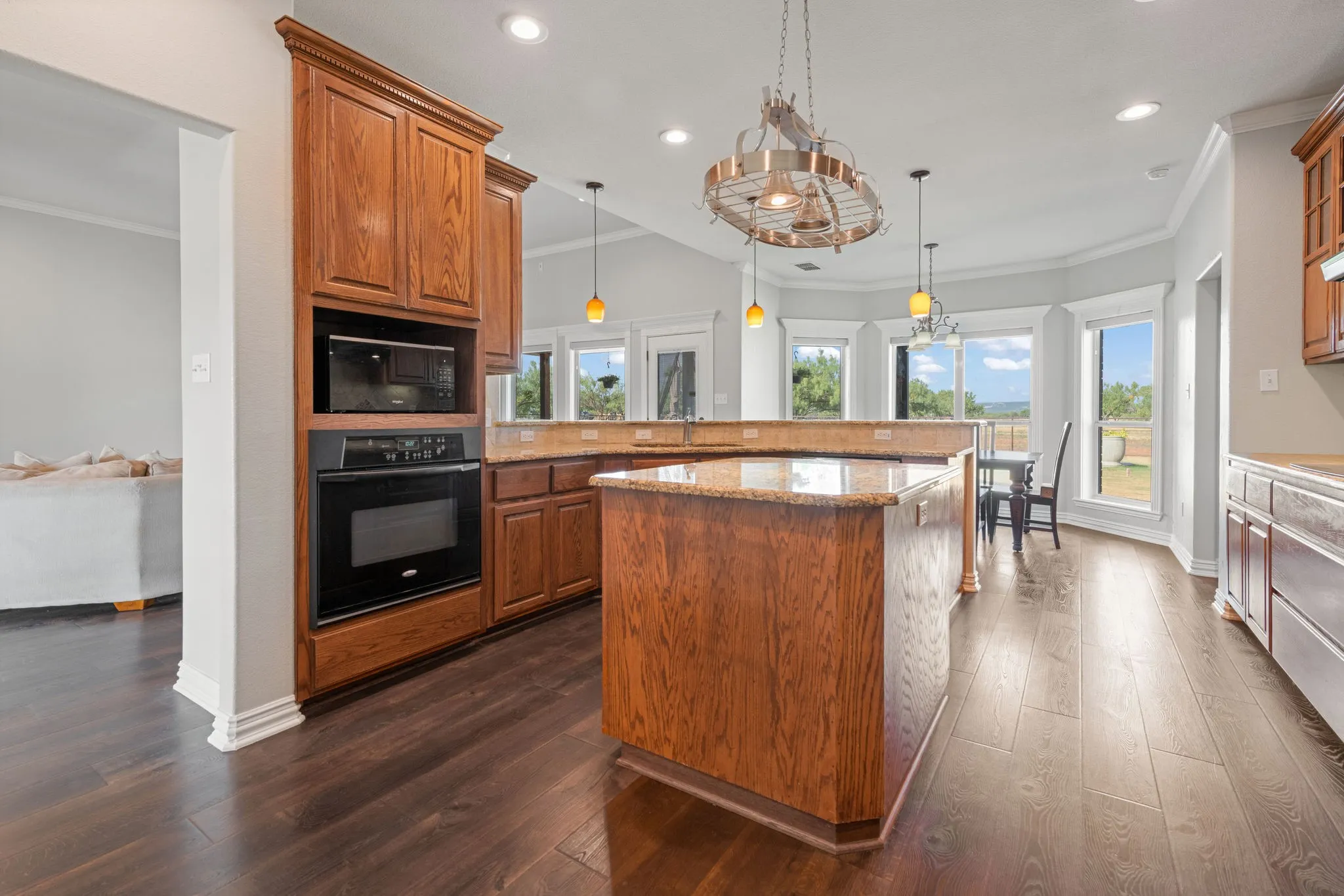 Kitchen featuring wood-finish LVP flooring, recessed and decorative lighting, and a center island with a granite countertop.