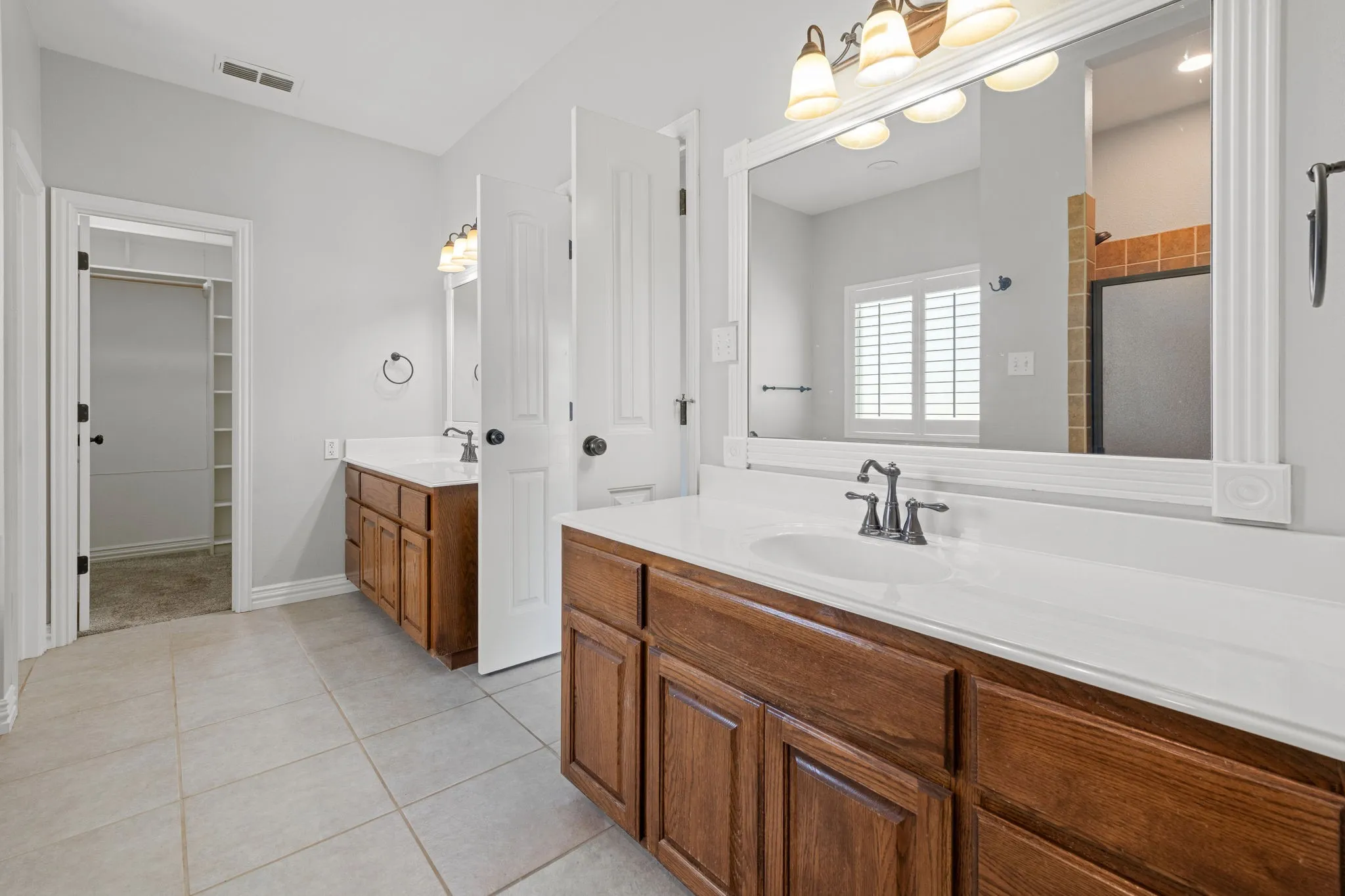 Dual vanity with oak cabinetry and white countertops and integrated sinks.