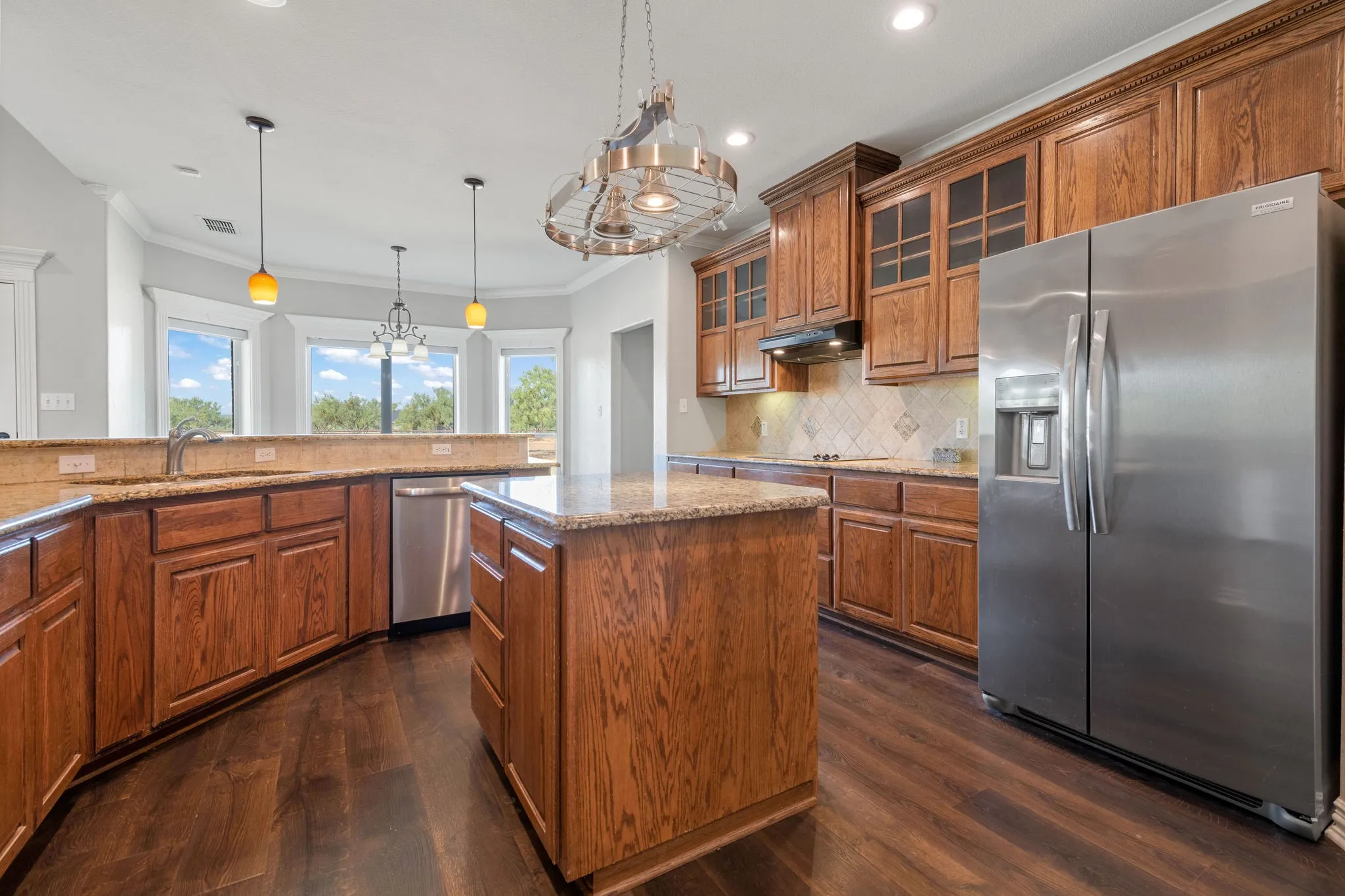 Expansive kitchen featuring wood-finish cabinetry, granite countertops, and island storage.