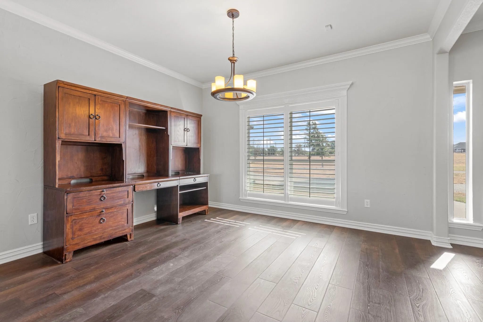 Wood-finish LVP flooring, bright painted and textured walls, crown molding, and a decorative chandelier.  Wood plank shutters.