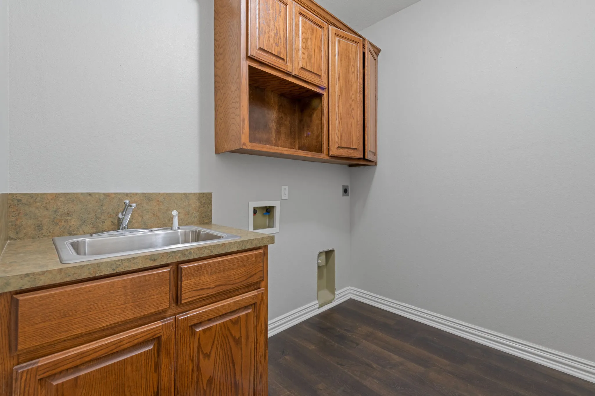 Wood-finish LVP flooring, oak cabinetry, stainless steel sink, and a countertop with integrated backsplash.