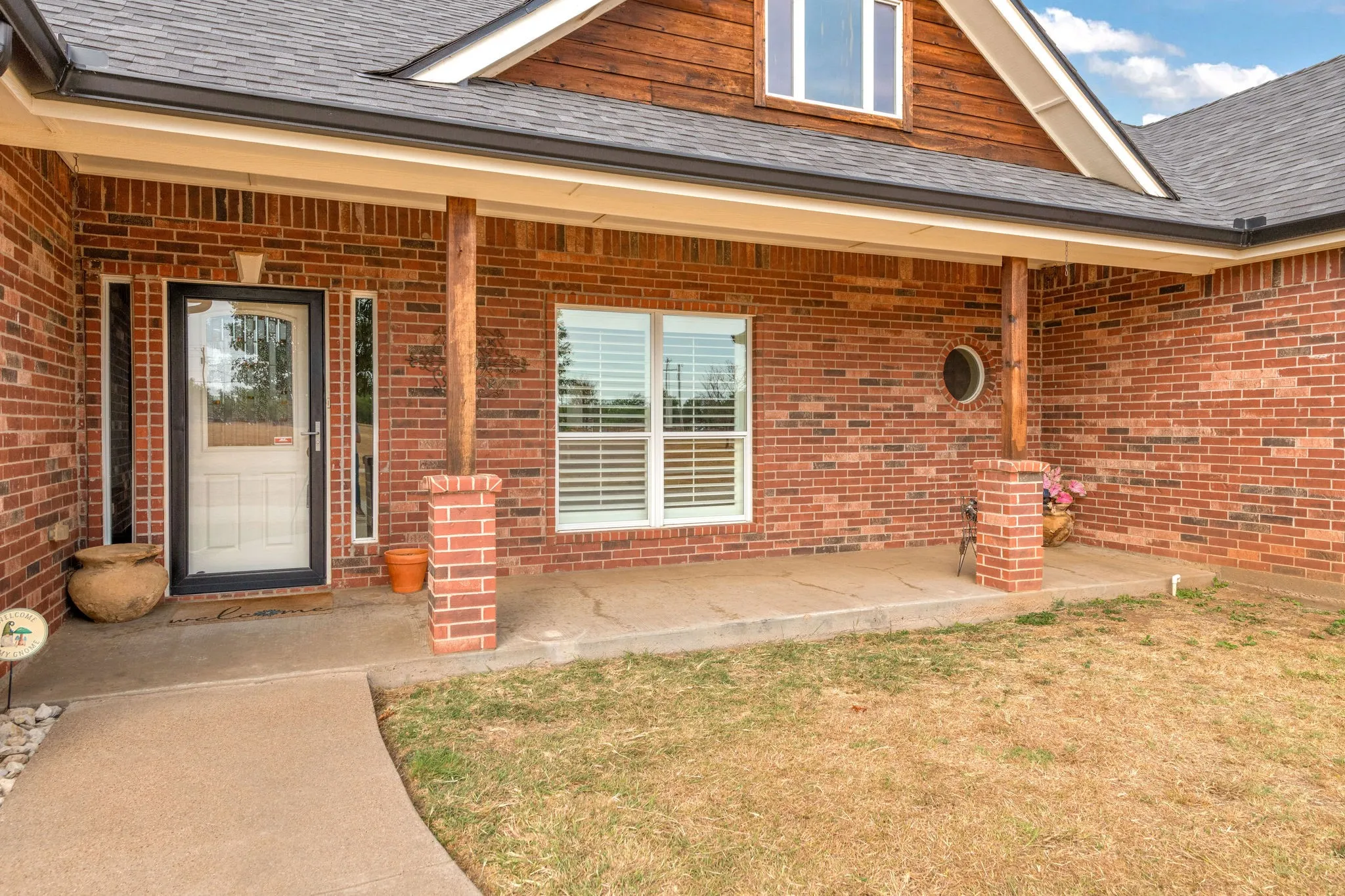 Brick exterior with a covered porch featuring wood posts and brick bases. Storm door.