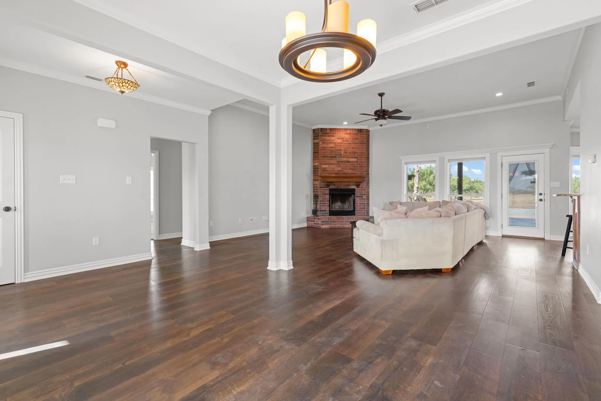 Brick corner fireplace with a wood mantle offset by double windows overlooking the back yard and inground pool.