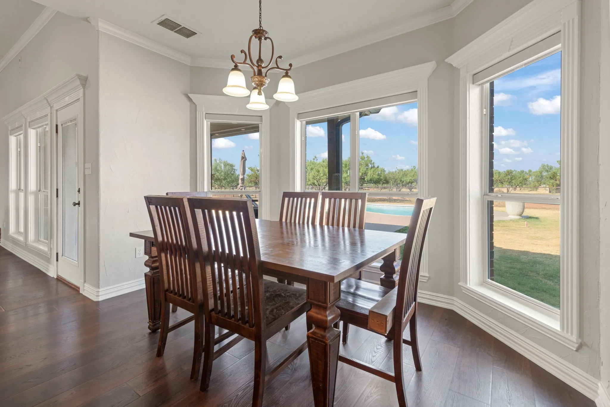 LVP flooring, decorative chandelier, white cased windows, and beautiful outdoor scenery.
