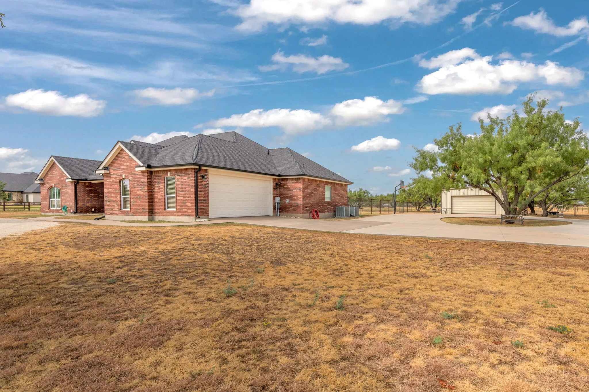 Brick exterior with a dark-pitched roof and gutters, 2 car attached garage, concrete driveway, and a shop.