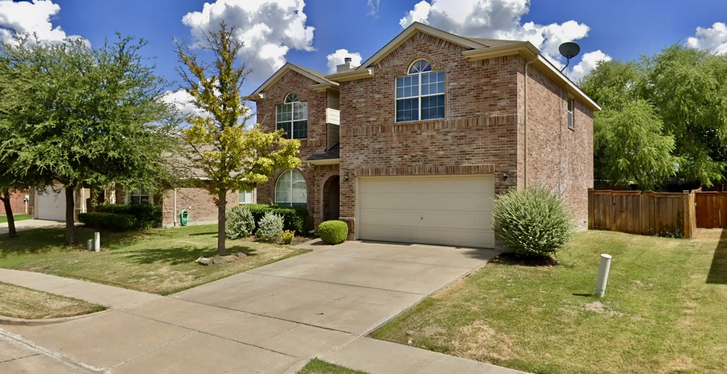 Brick exterior with arched windows, an attached two-car garage, and a concrete driveway