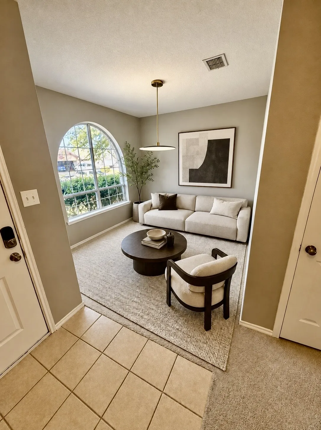 Arch-top window, recessed ceiling, pendant lighting, neutral wall tones, tile flooring at entry