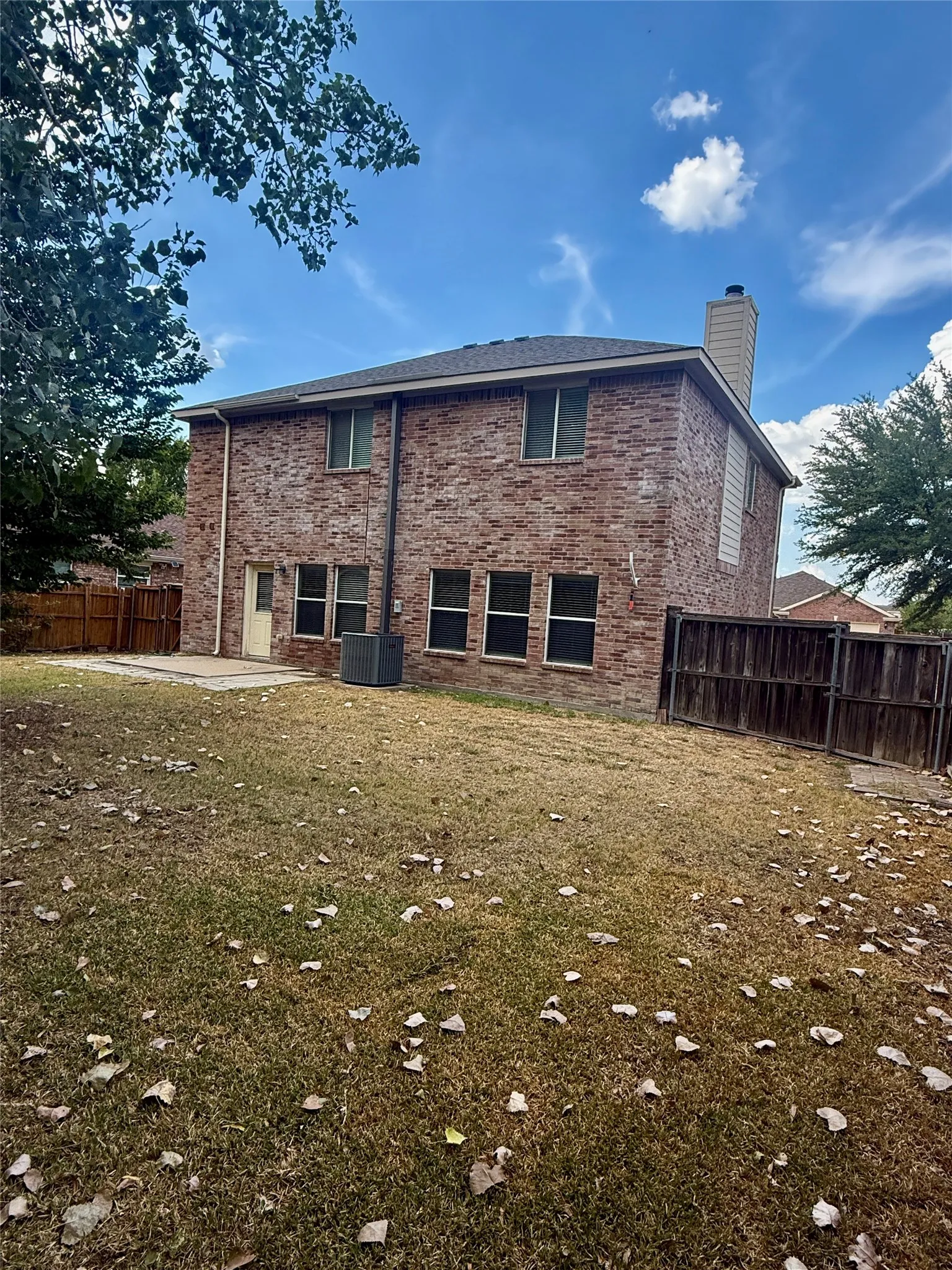 Brick exterior with multiple windows and a shingle roof