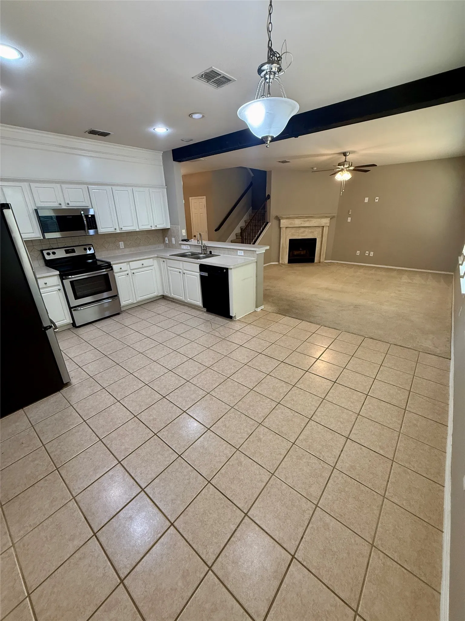 White cabinetry, stainless steel appliances, and a kitchen island with a sink