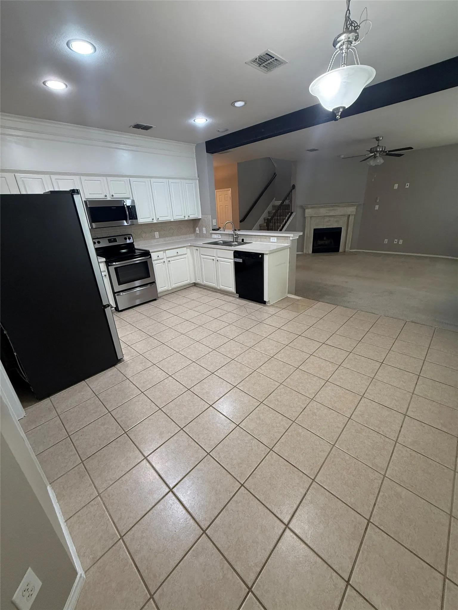 Kitchen with tile flooring, white cabinetry, stainless steel appliances, and a built-in dishwasher