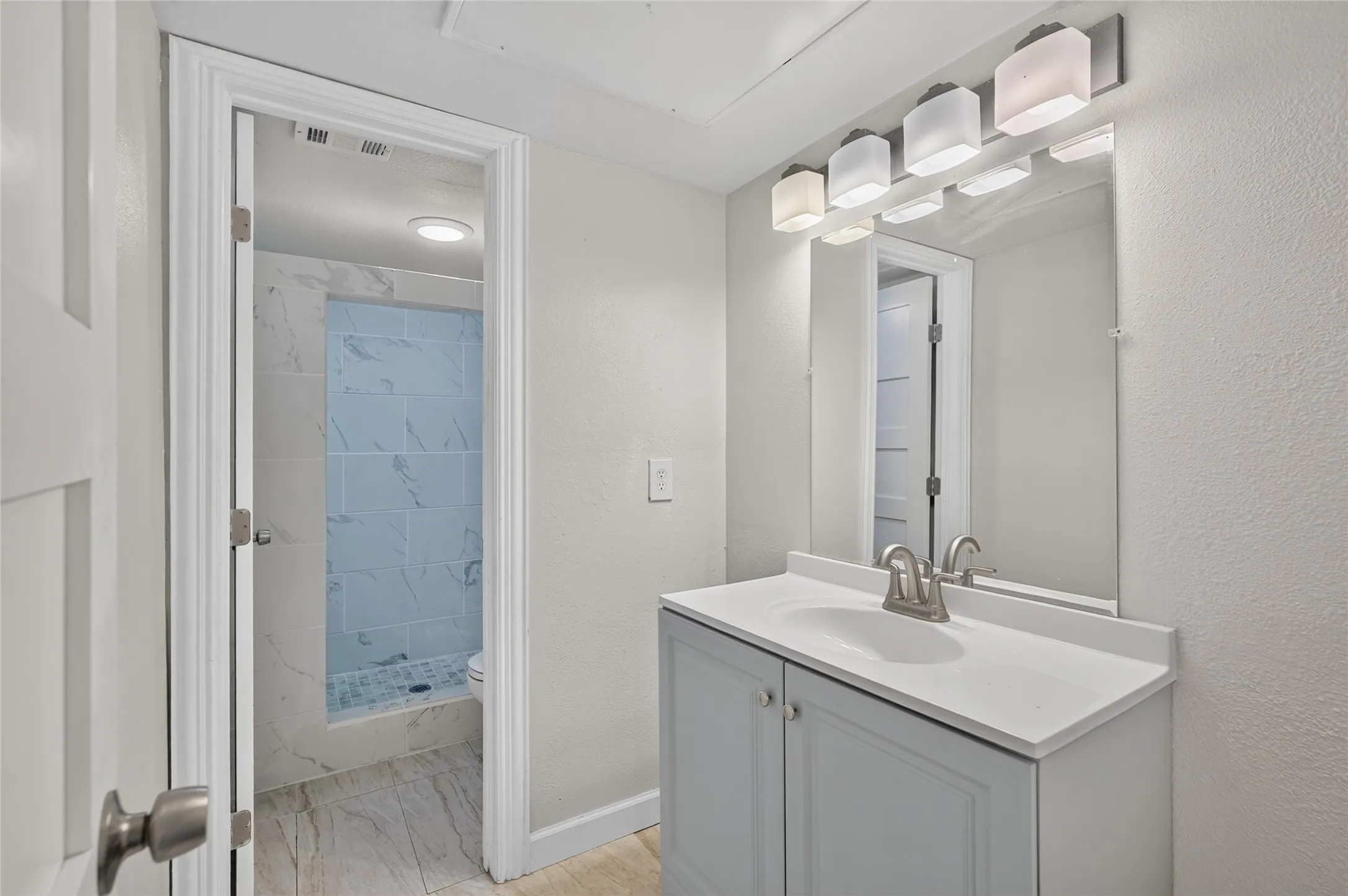 Single vanity with integrated sink, brushed nickel faucet, and overhead light fixture