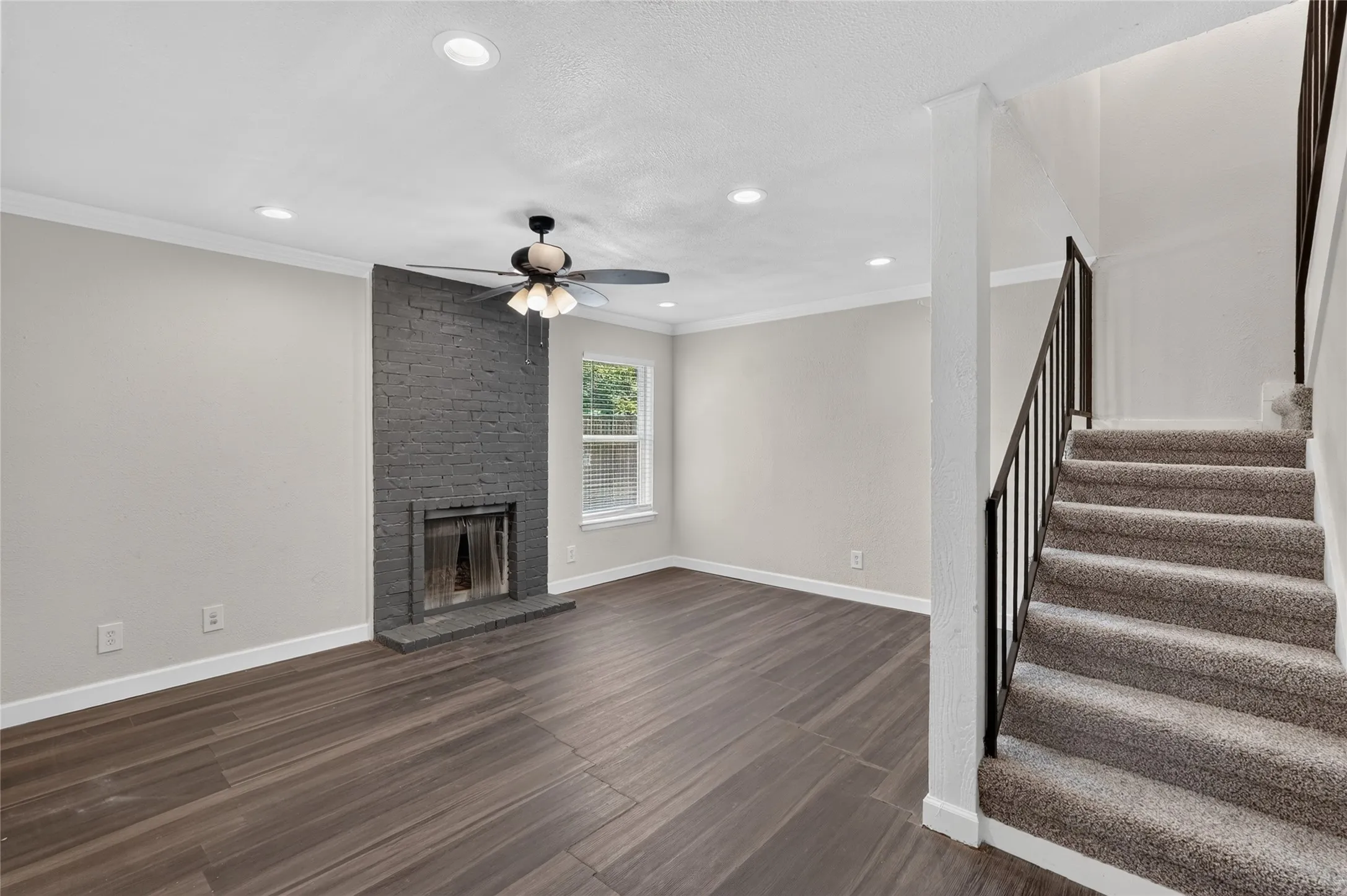 Living area featuring wood-finish flooring, a painted brick fireplace, recessed lighting, and a ceiling fan