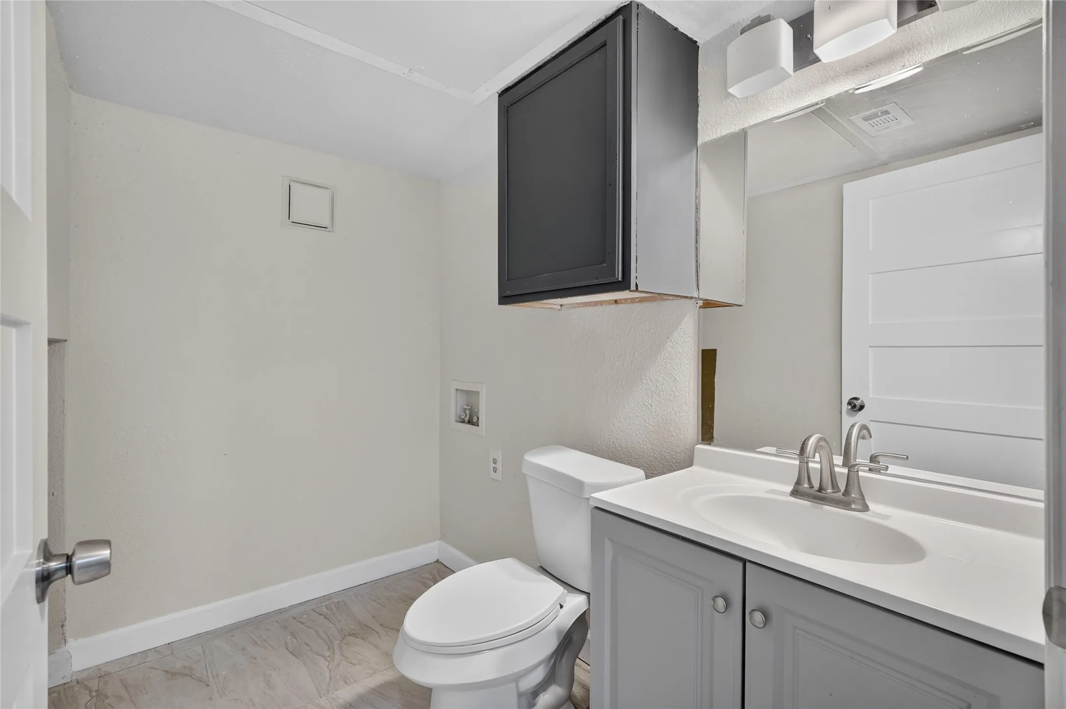 Vanity with a single basin sink, wall-mounted lighting, and built-in cabinetry