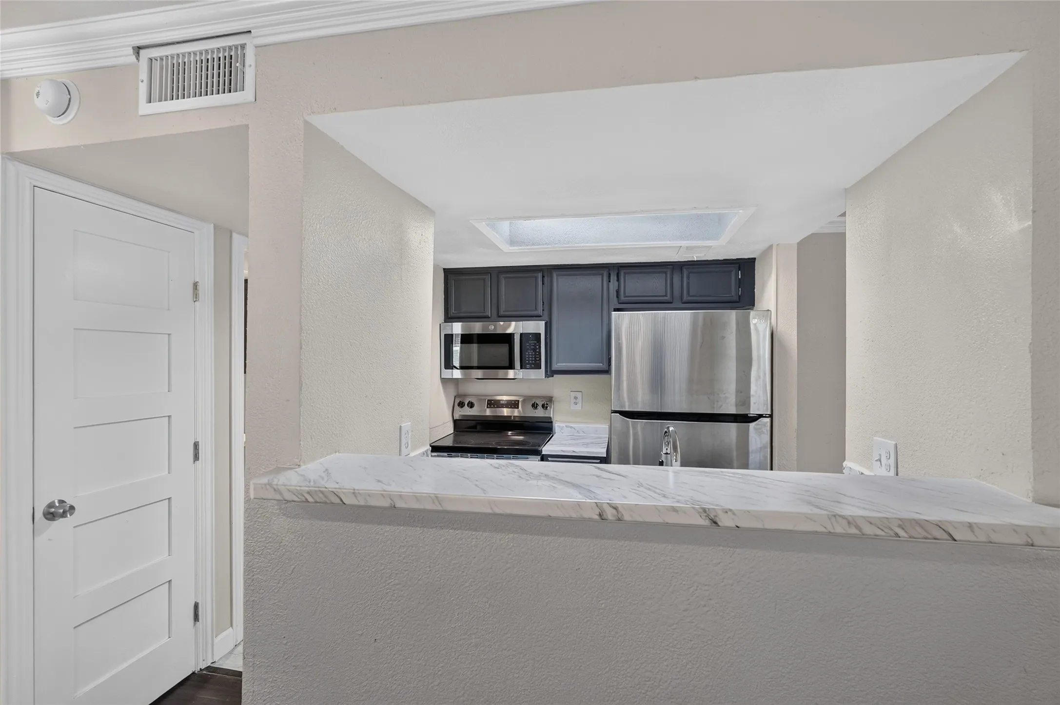 Kitchen with dark cabinetry, stainless steel appliances, and a skylight