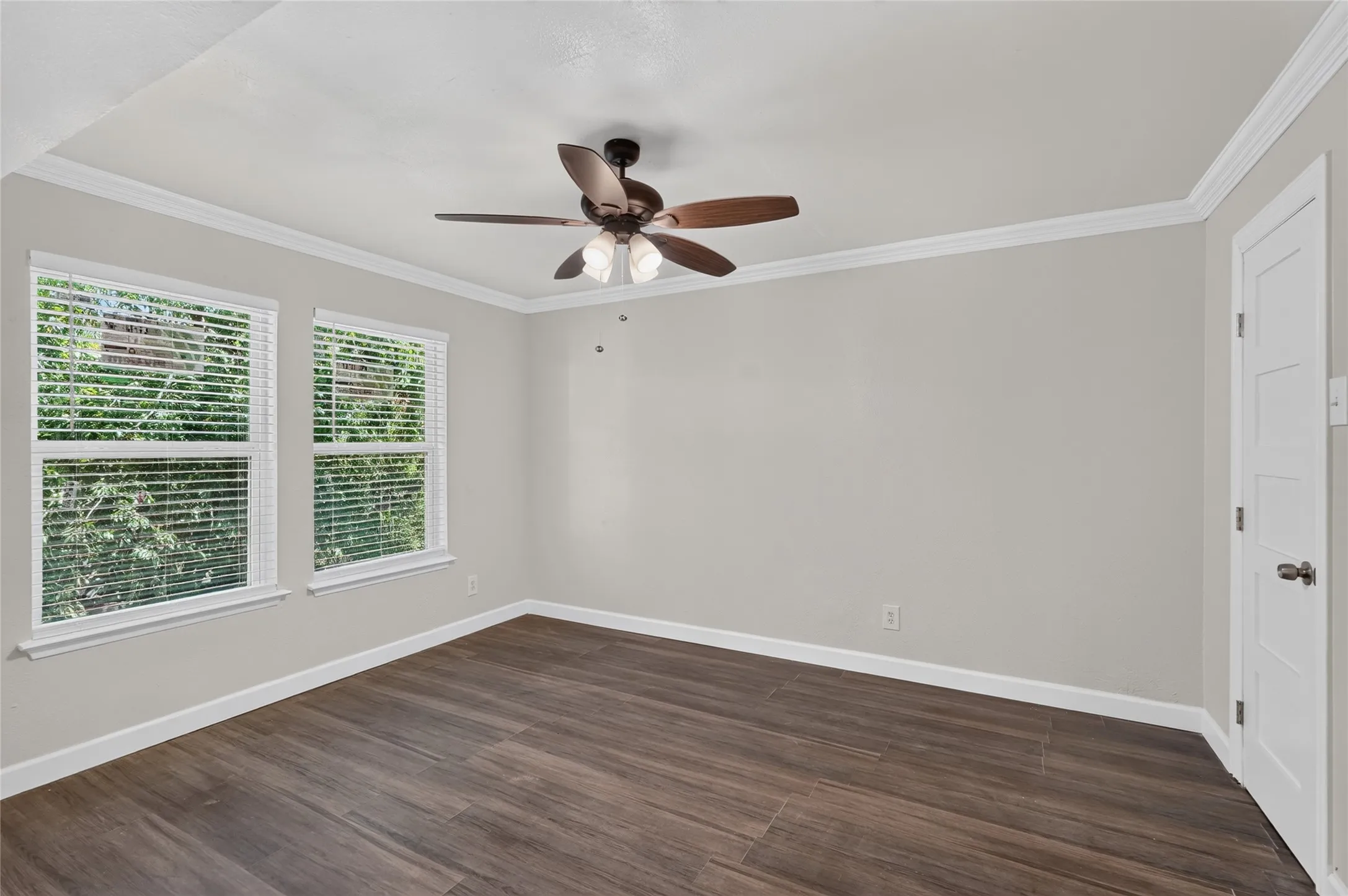 Wood-finish flooring, crisp white trim, and a ceiling fan with integrated lighting
