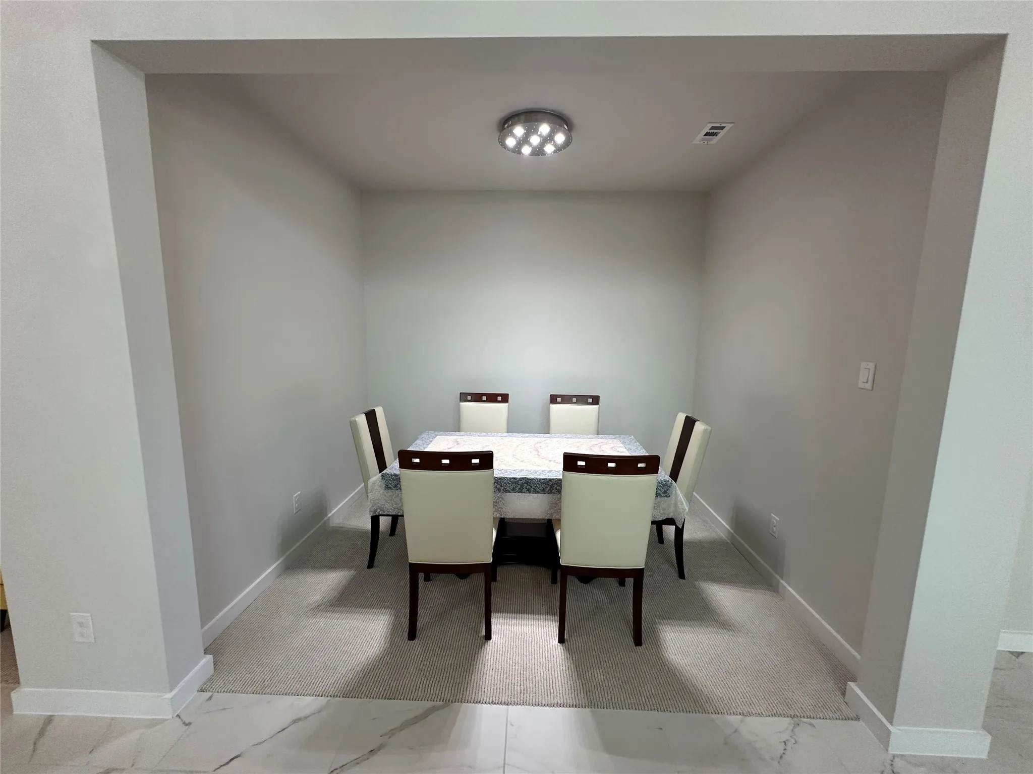 Recessed dining area with carpeted flooring and a flush-mount ceiling light fixture