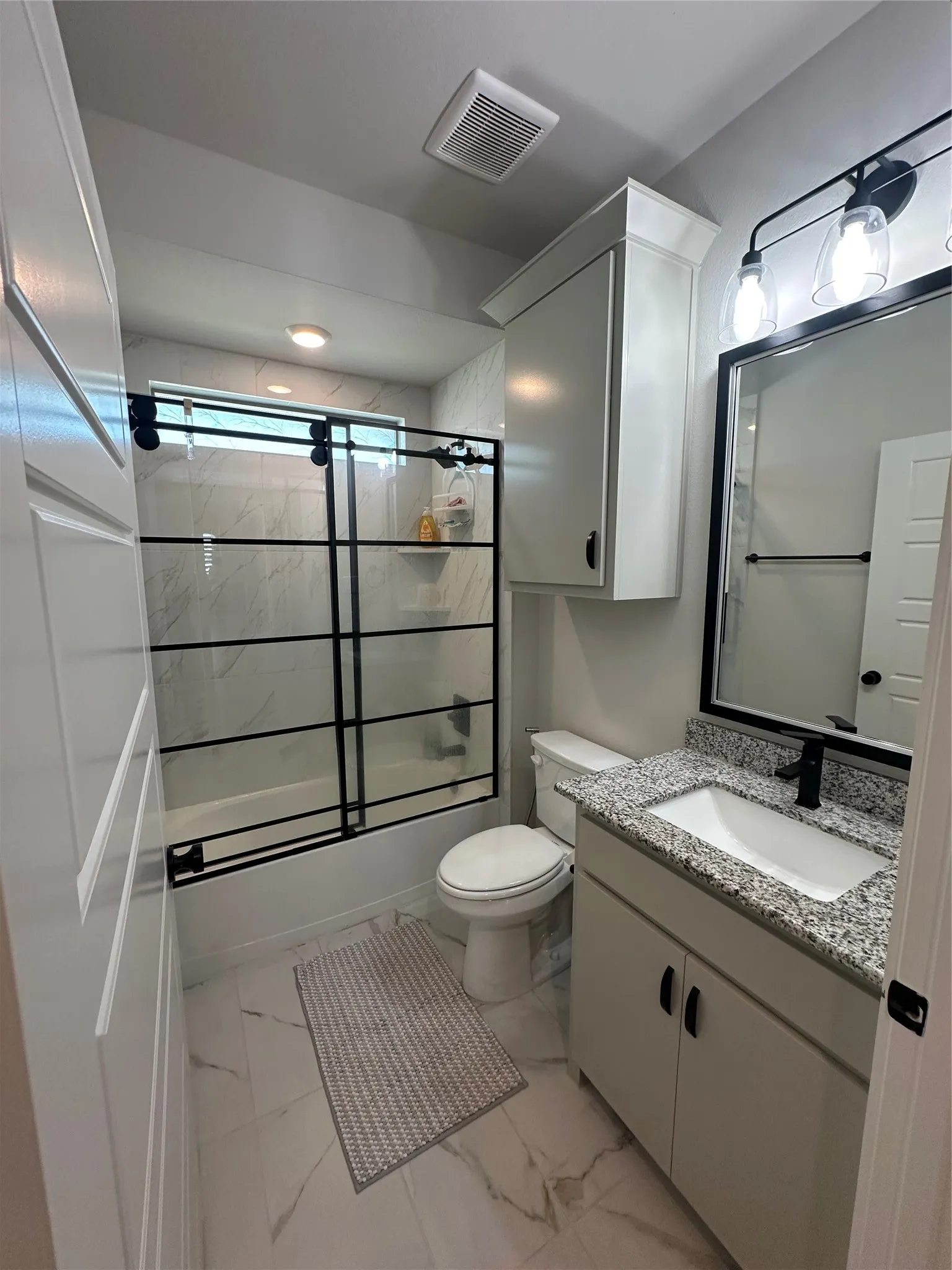 Bathroom featuring a built-in vanity with granite-finish countertop, a rectangular undermount sink, and a black-framed mirror