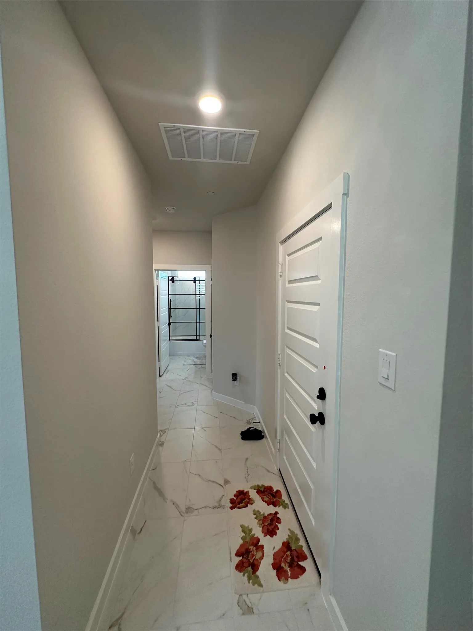 Hallway with white tile flooring and a white paneled door